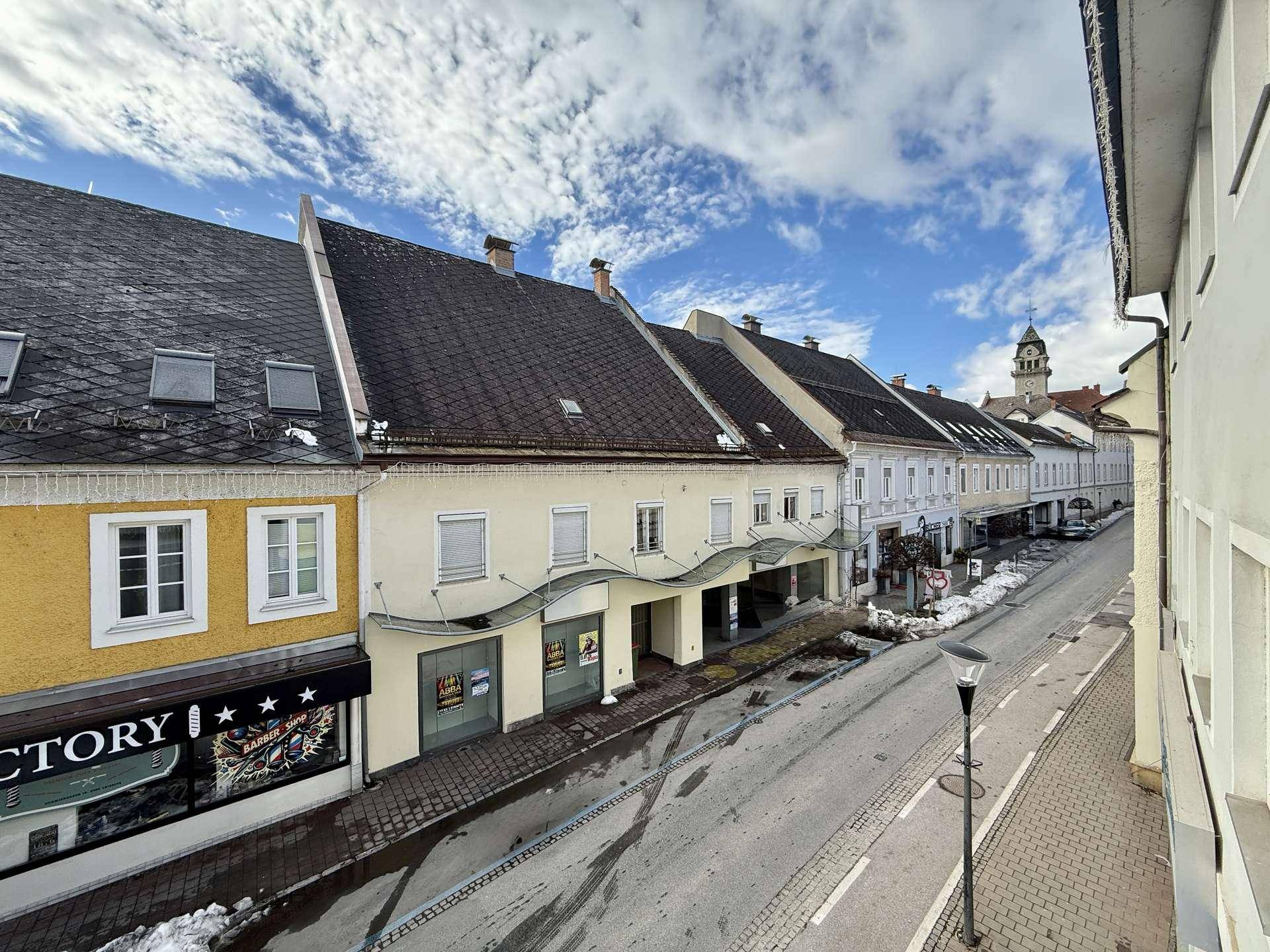 Blick von oben auf eine belebte Straße mit Geschäften und historischen Gebäuden.