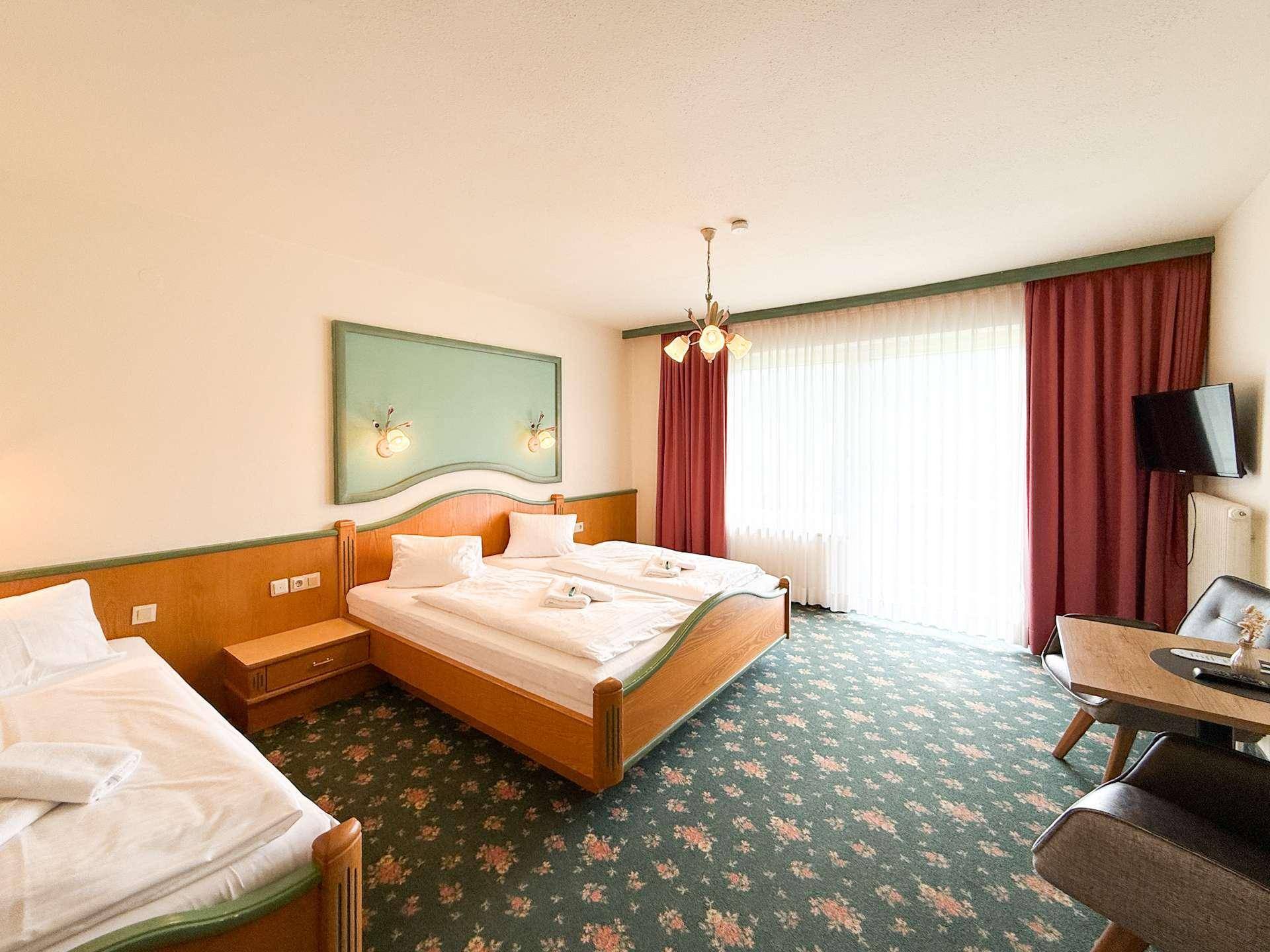 Gemütliches Schlafzimmer mit zwei Einzelbetten, Teppichboden und Zugang zu einem Balkon.