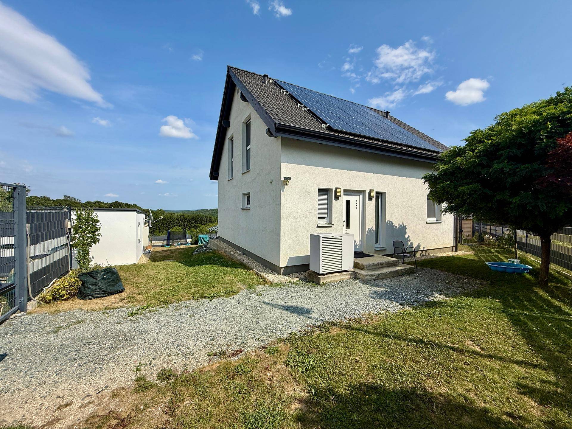 Modernes Einfamilienhaus mit Photovoltaikanlage auf dem Dach und gepflegtem Vorgarten.