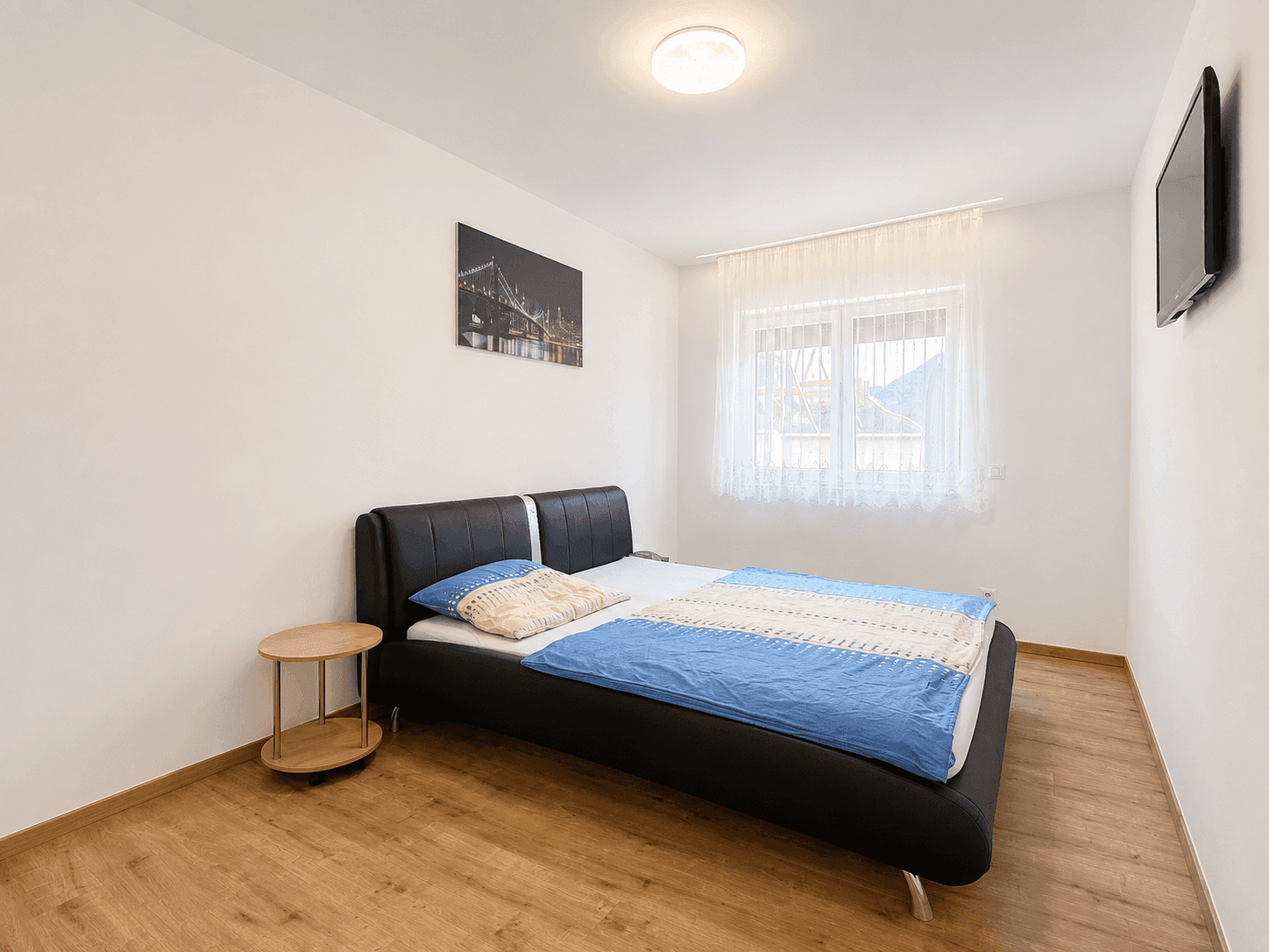 Gemütliches Schlafzimmer mit Doppelbett, Holzboden und Fenster mit Blick auf die Umgebung.