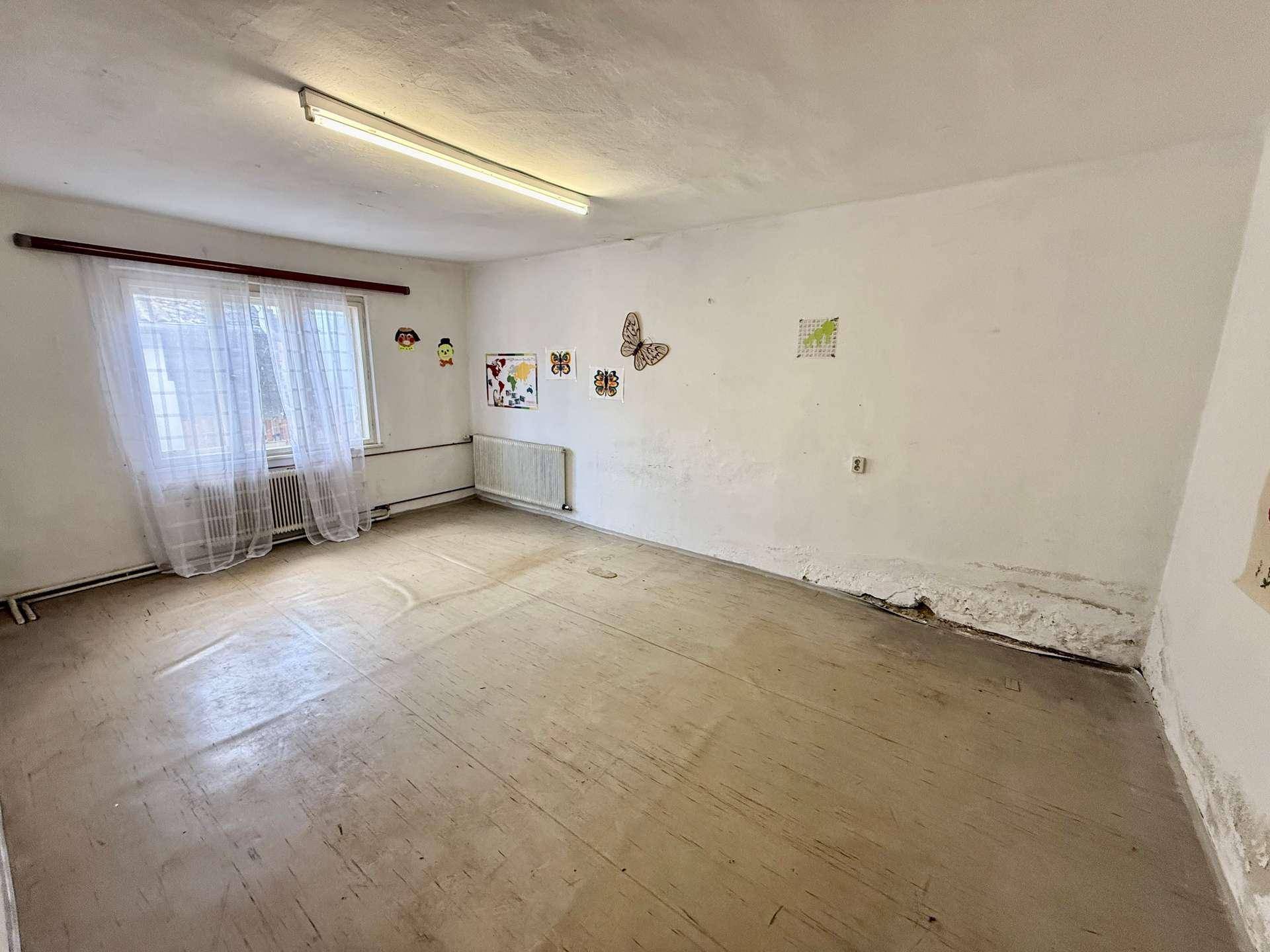 Einfacher Raum mit Fenster, bunten Wandbildern und sichtbaren Gebrauchsspuren.