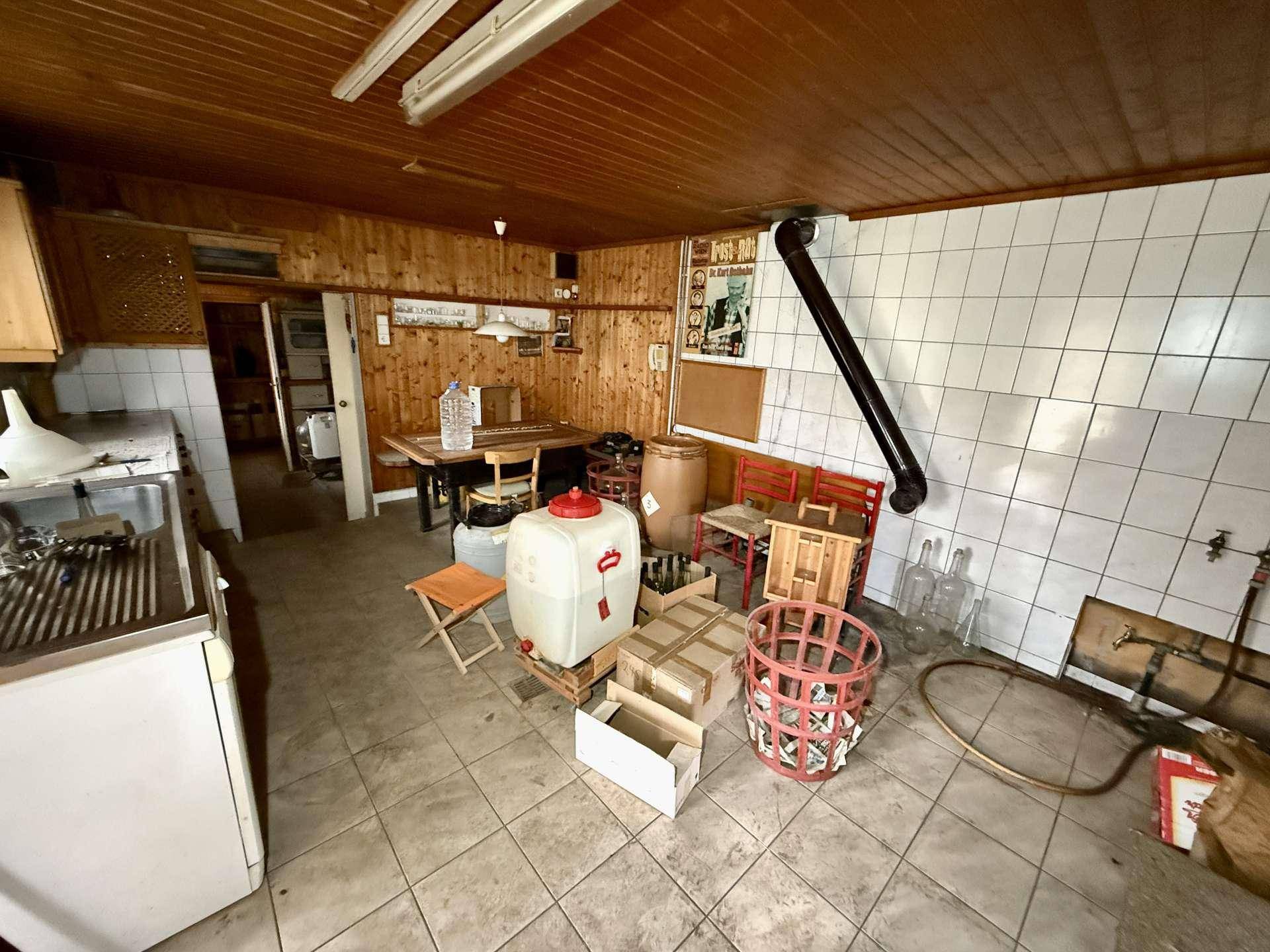 Rustikaler Wirtschaftsraum mit Holzverkleidung, Fliesenboden und Arbeitsbereich für verschiedene Tätigkeiten.
