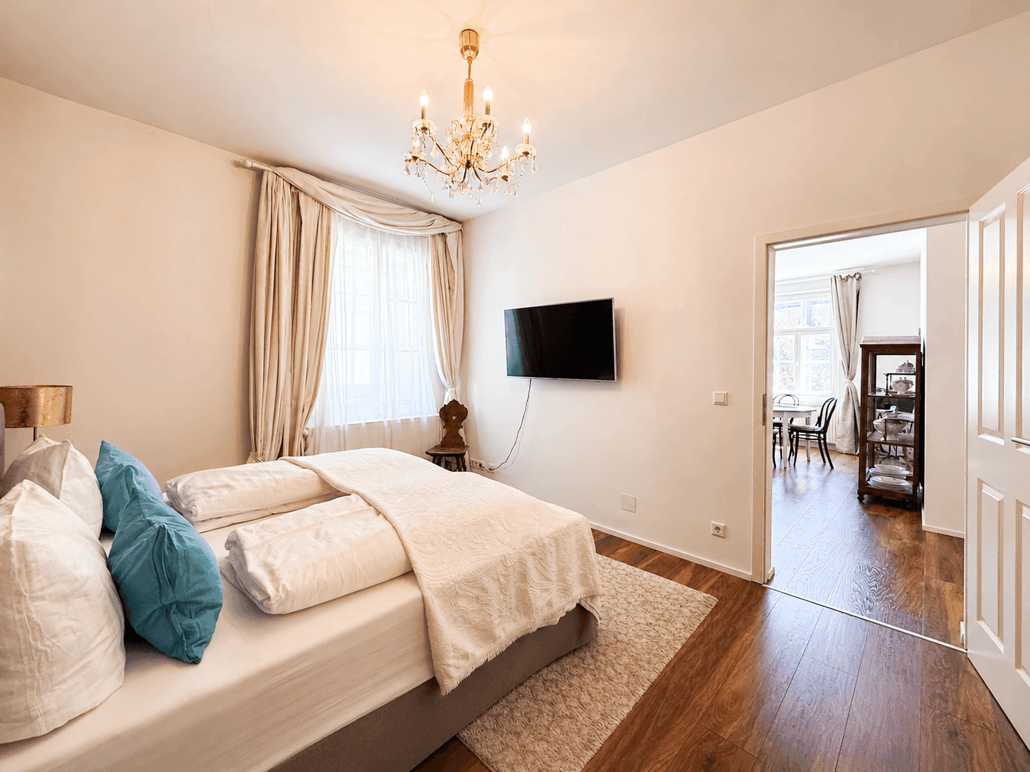 Schlafzimmer mit Holzboden, großem Bett und Zugang zum Essbereich.