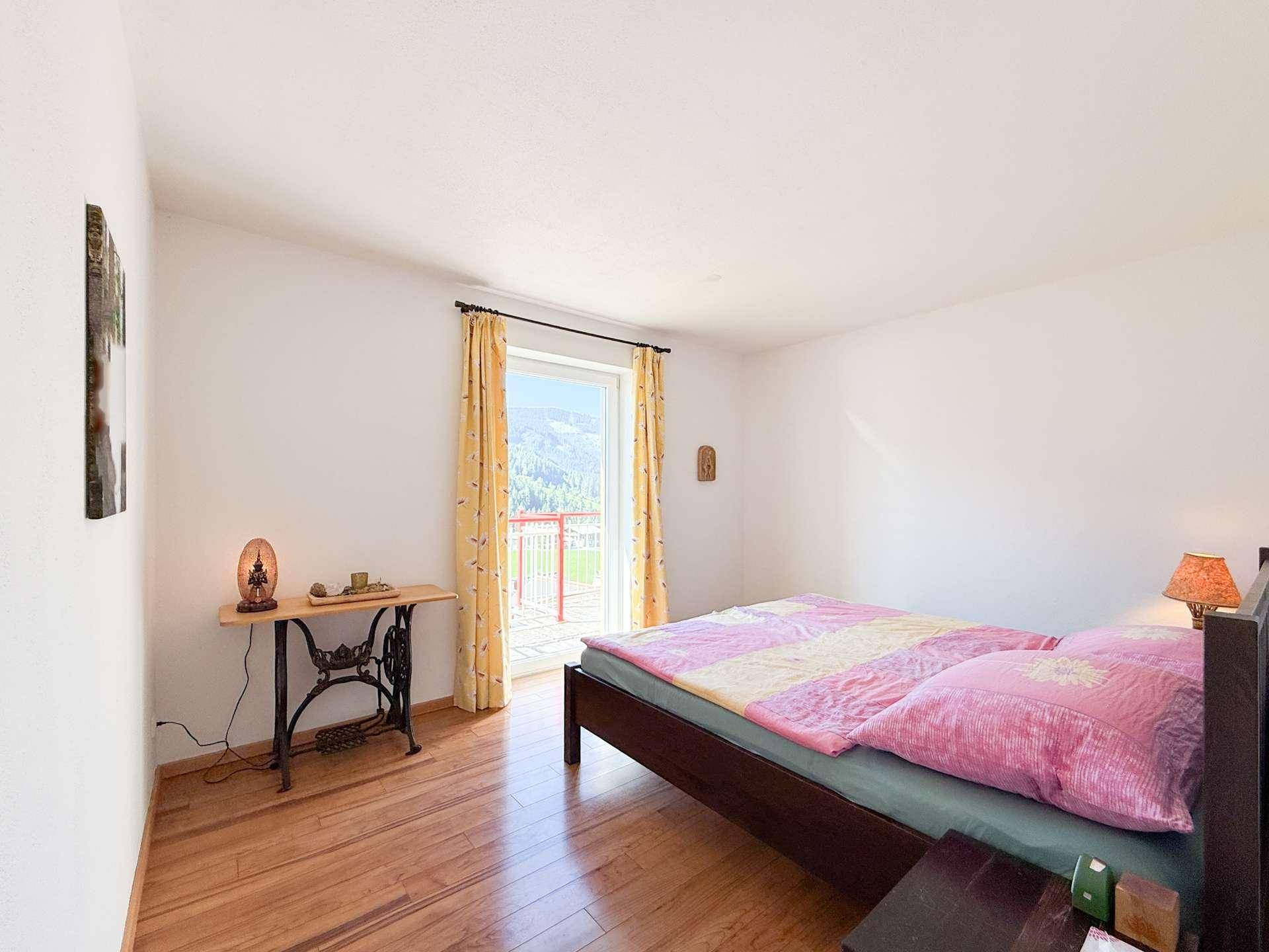 Geräumiges Schlafzimmer mit Holzboden und Zugang zu einem Balkon mit Bergblick.
