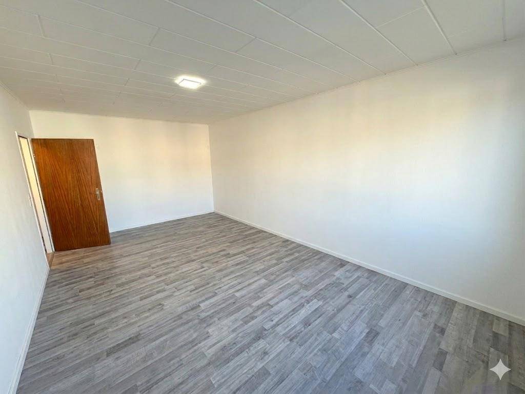 Leeres Zimmer mit Laminatboden und einer Holztür, bereit für die individuelle Gestaltung.