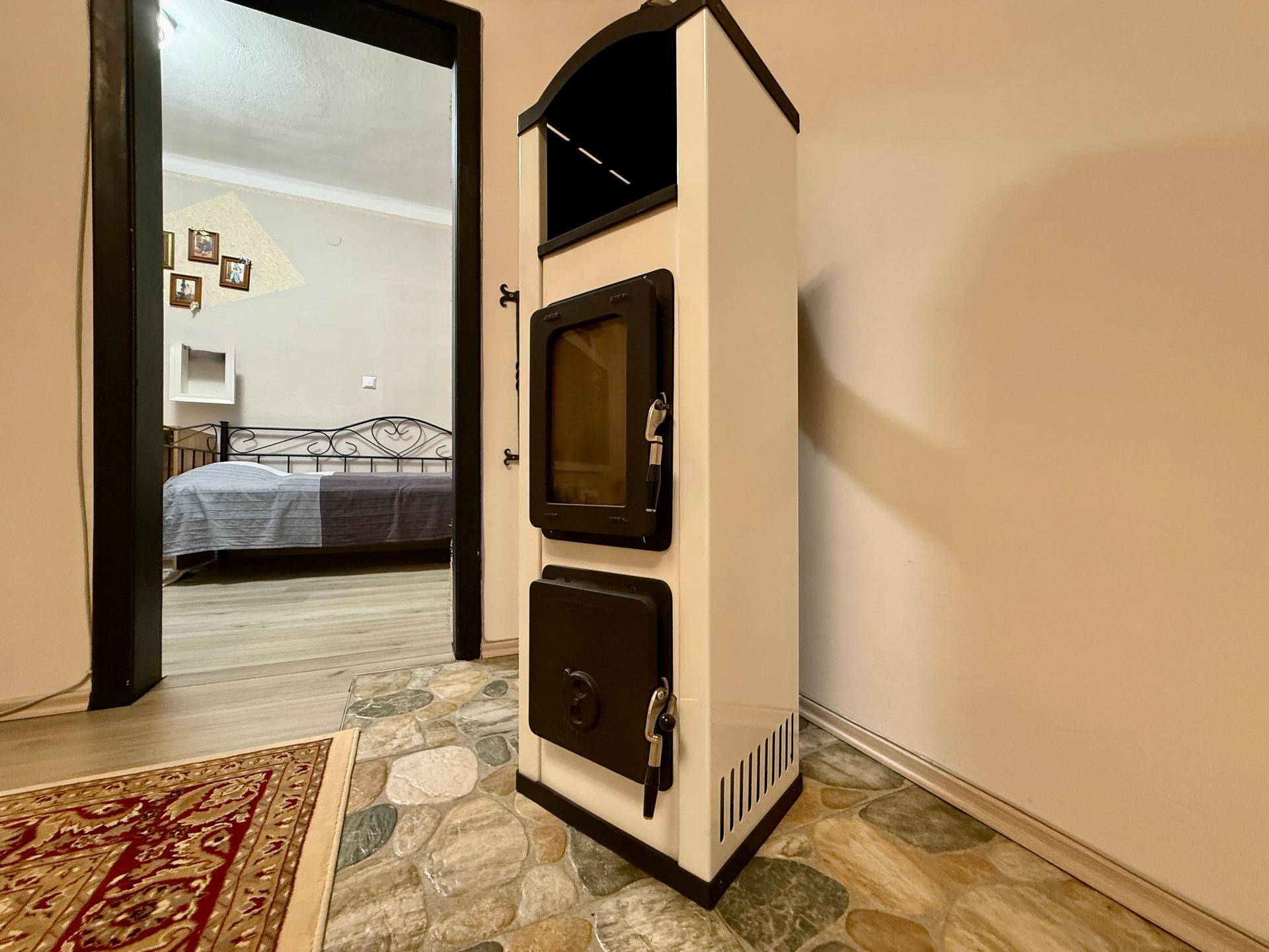 Moderner Holzofen im Wohnbereich mit Blick auf das angrenzende Schlafzimmer.