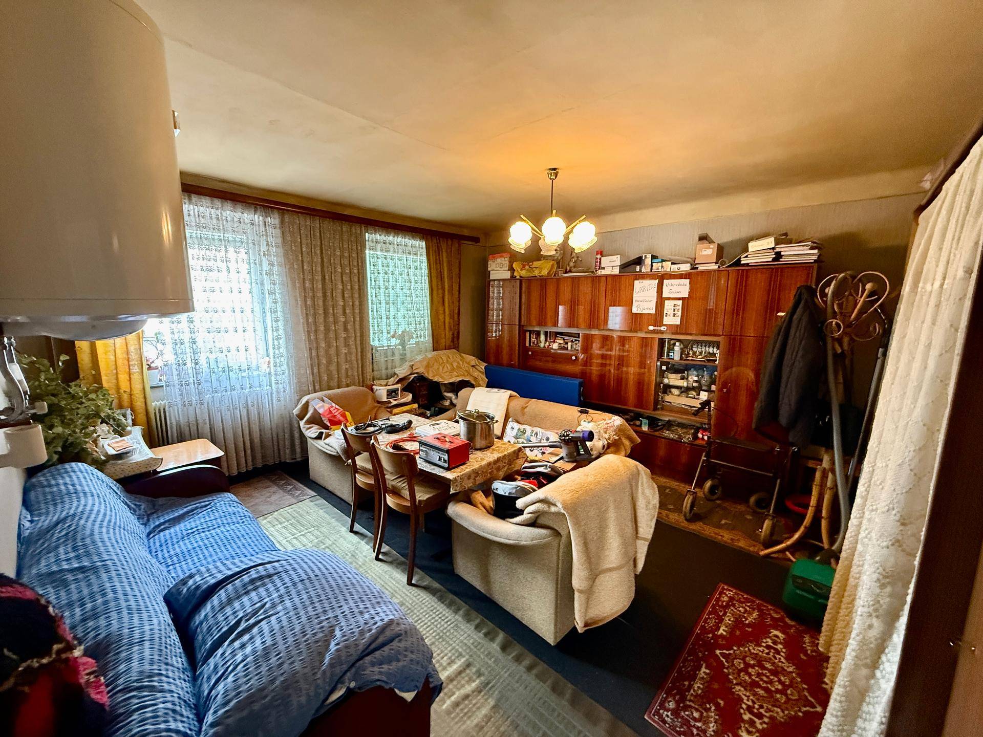 Gemütliches Wohnzimmer mit traditionellen Möbeln, Esstisch und einem großen Holzschrank.