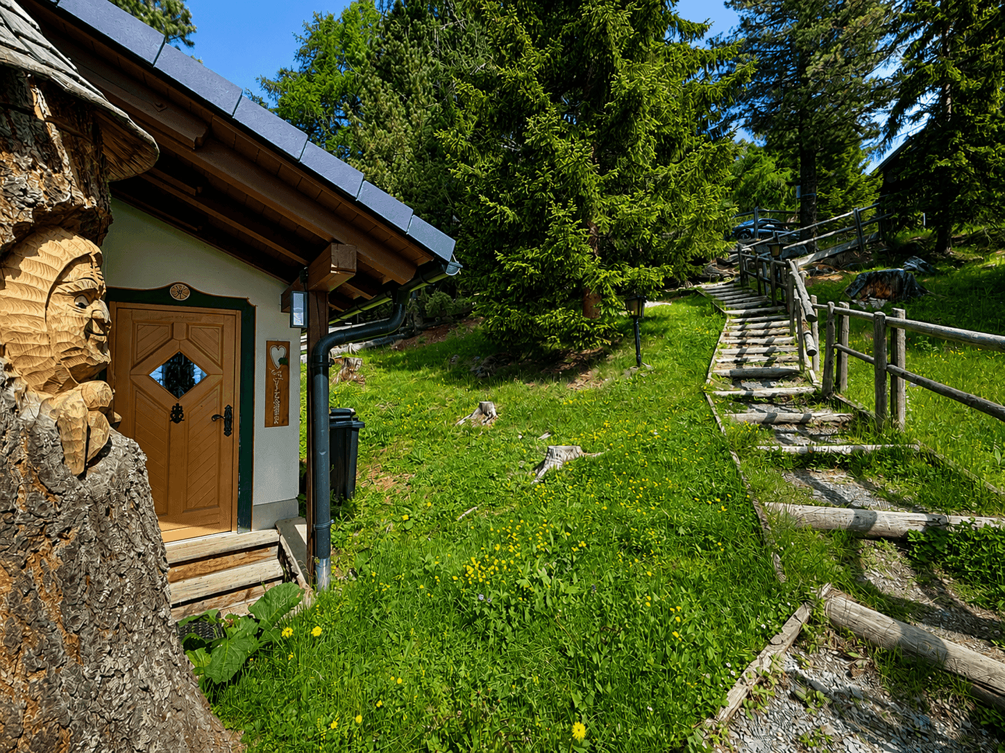 Idyllischer Gartenweg mit Holzstufen und üppigem Grün, der zum Haus führt.