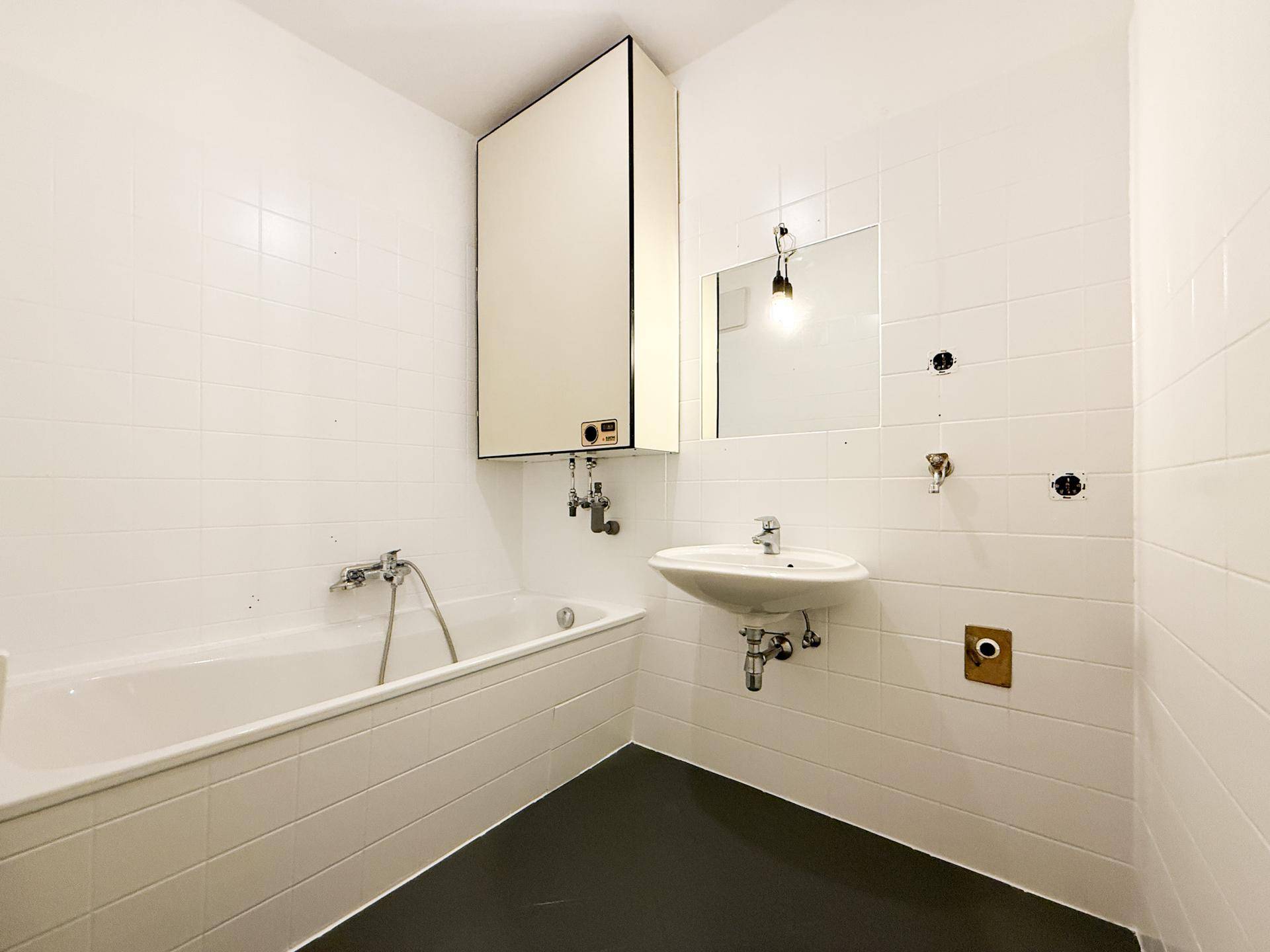 Badezimmer mit Badewanne, Waschbecken und weißen Fliesen, funktional und hell.