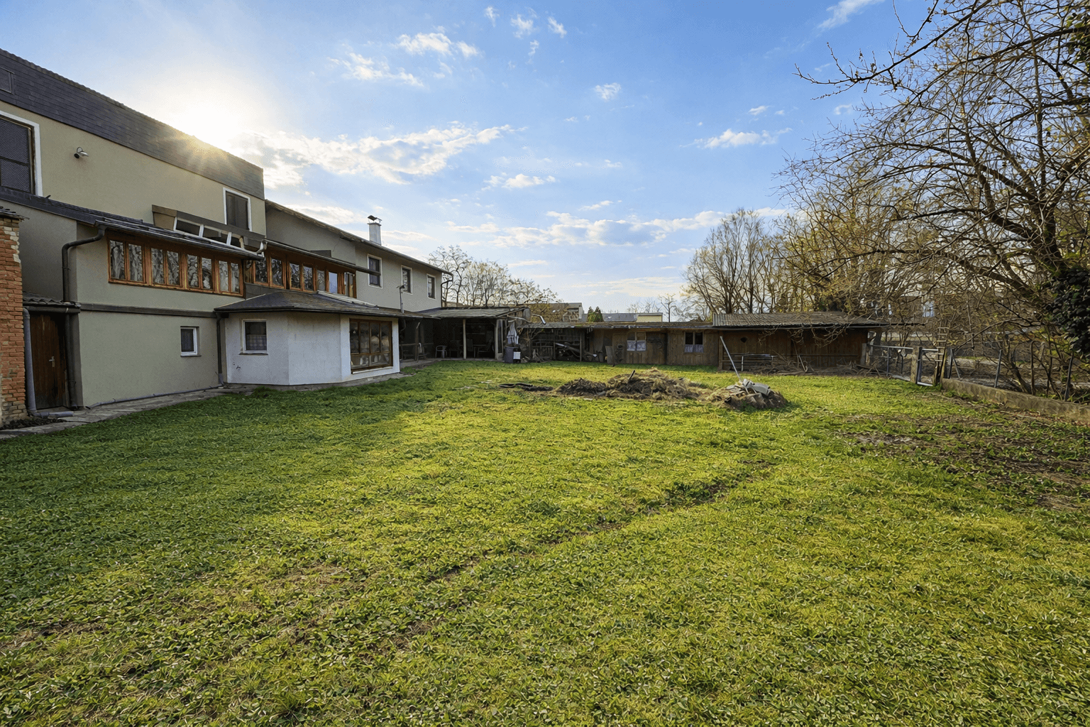 Weitläufiger Gartenbereich mit Rasenfläche und Blick auf das Gebäude unter sonnigem Himmel.