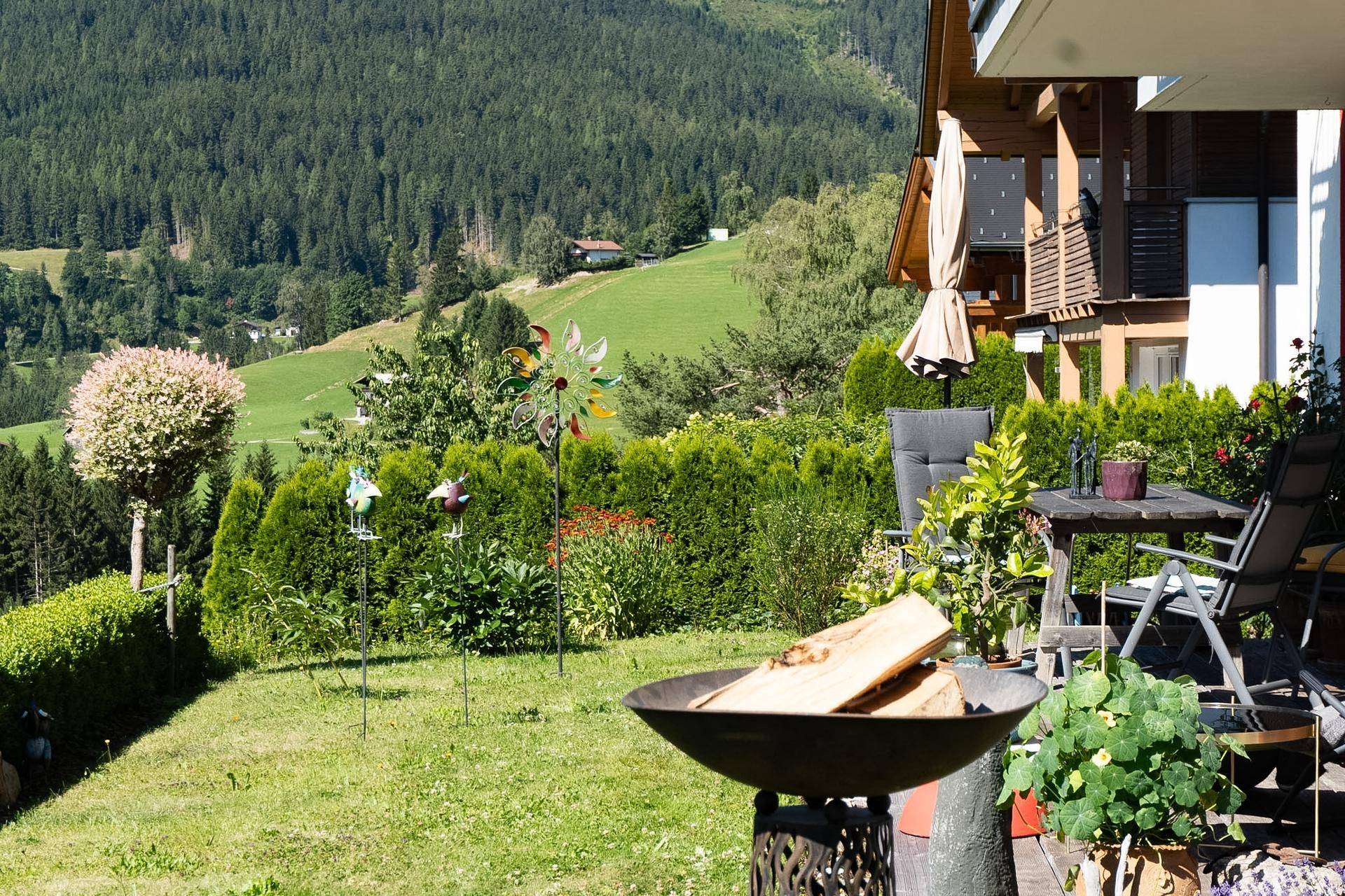 Gepflegter Gartenbereich mit Feuerstelle, Terrasse und üppiger Bepflanzung.