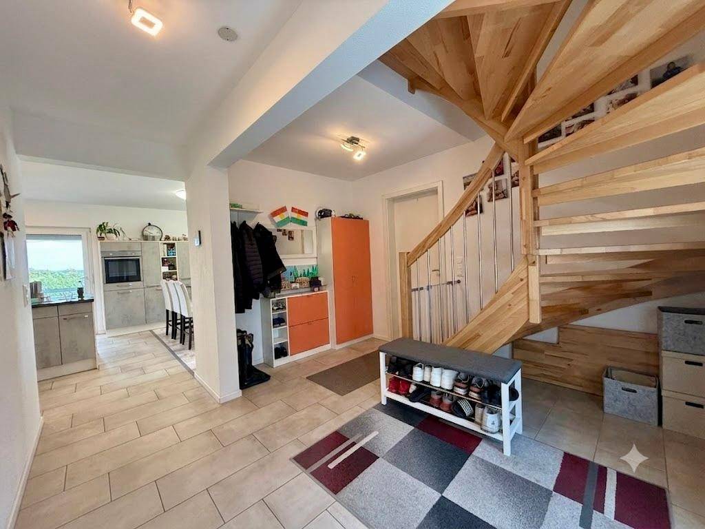 Heller Eingangsbereich mit eleganter Holzwendeltreppe und praktischem Schuhregal.