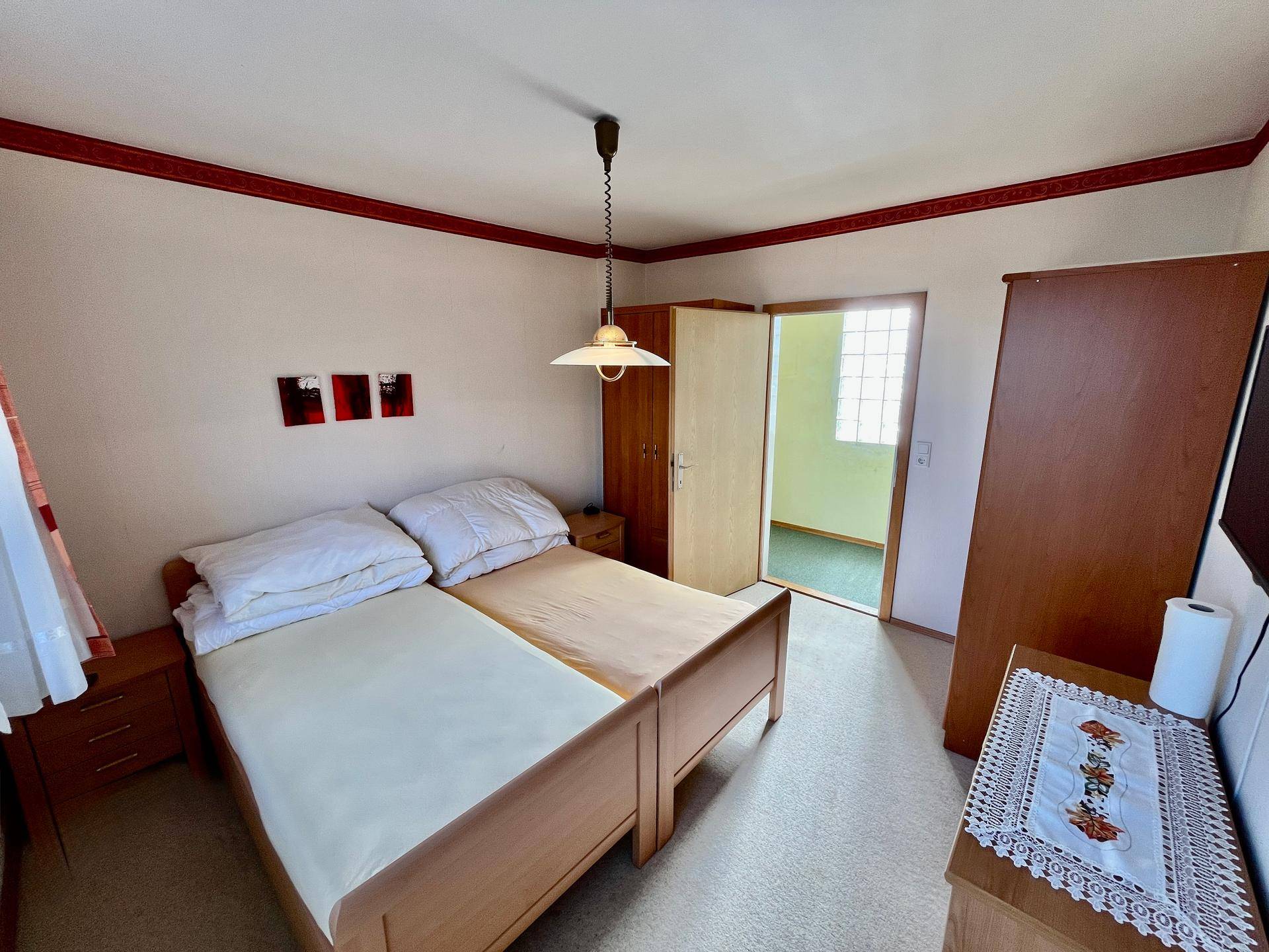 Gemütliches Schlafzimmer mit zwei Einzelbetten, Teppichboden und einfacher Einrichtung.
