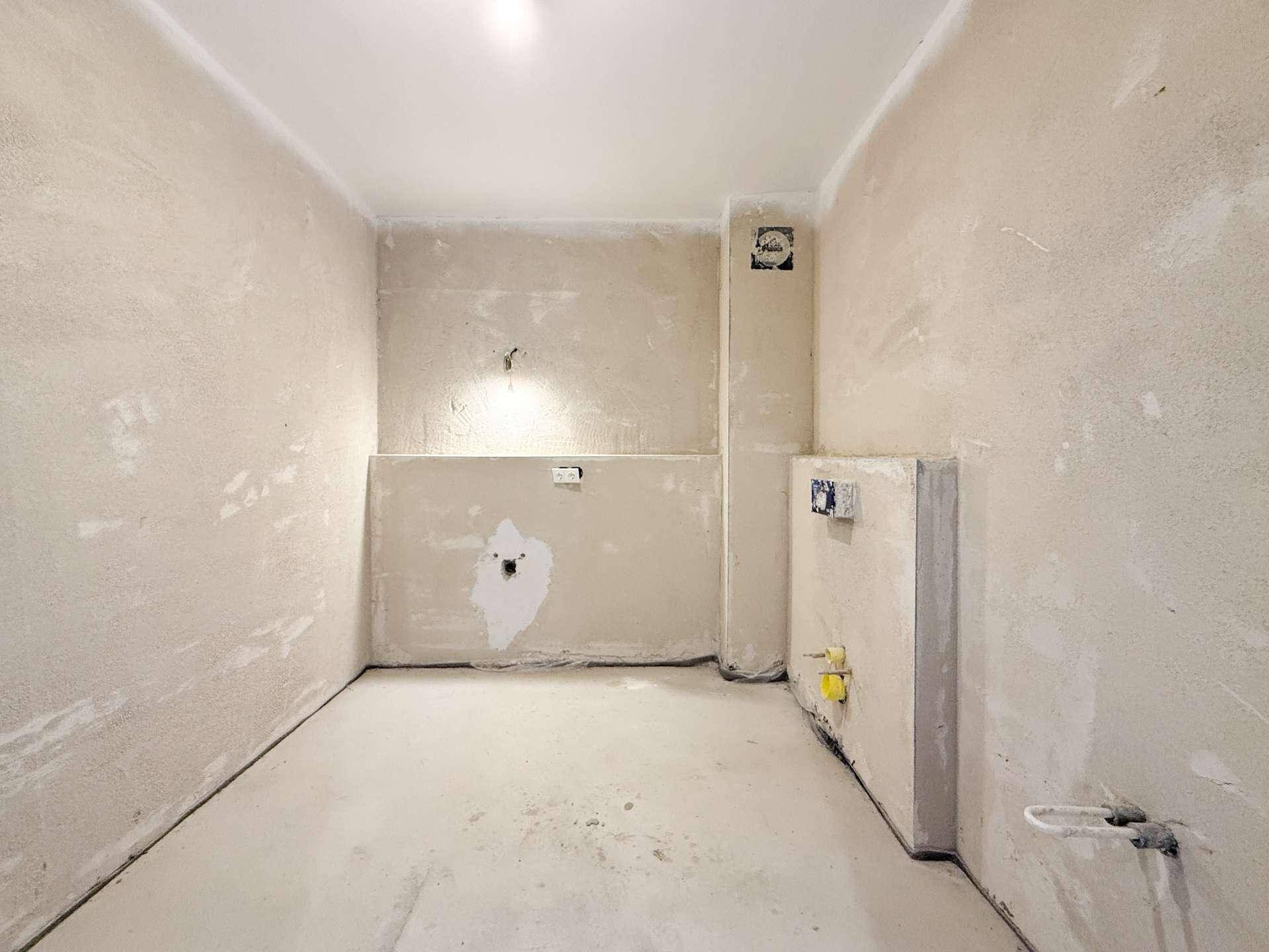Badezimmer im Rohbau mit sichtbaren Installationen und unfertigen Wänden.