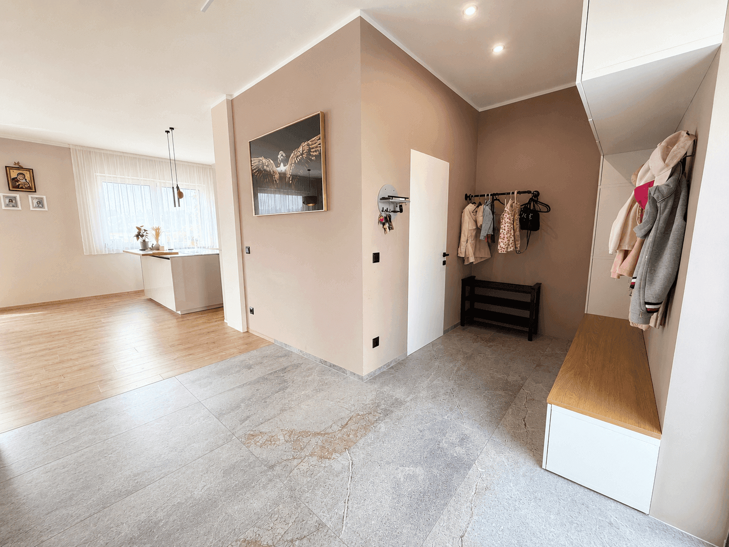 Geräumiger Eingangsbereich mit Garderobe, Sitzbank und offenem Übergang zur modernen Küche.