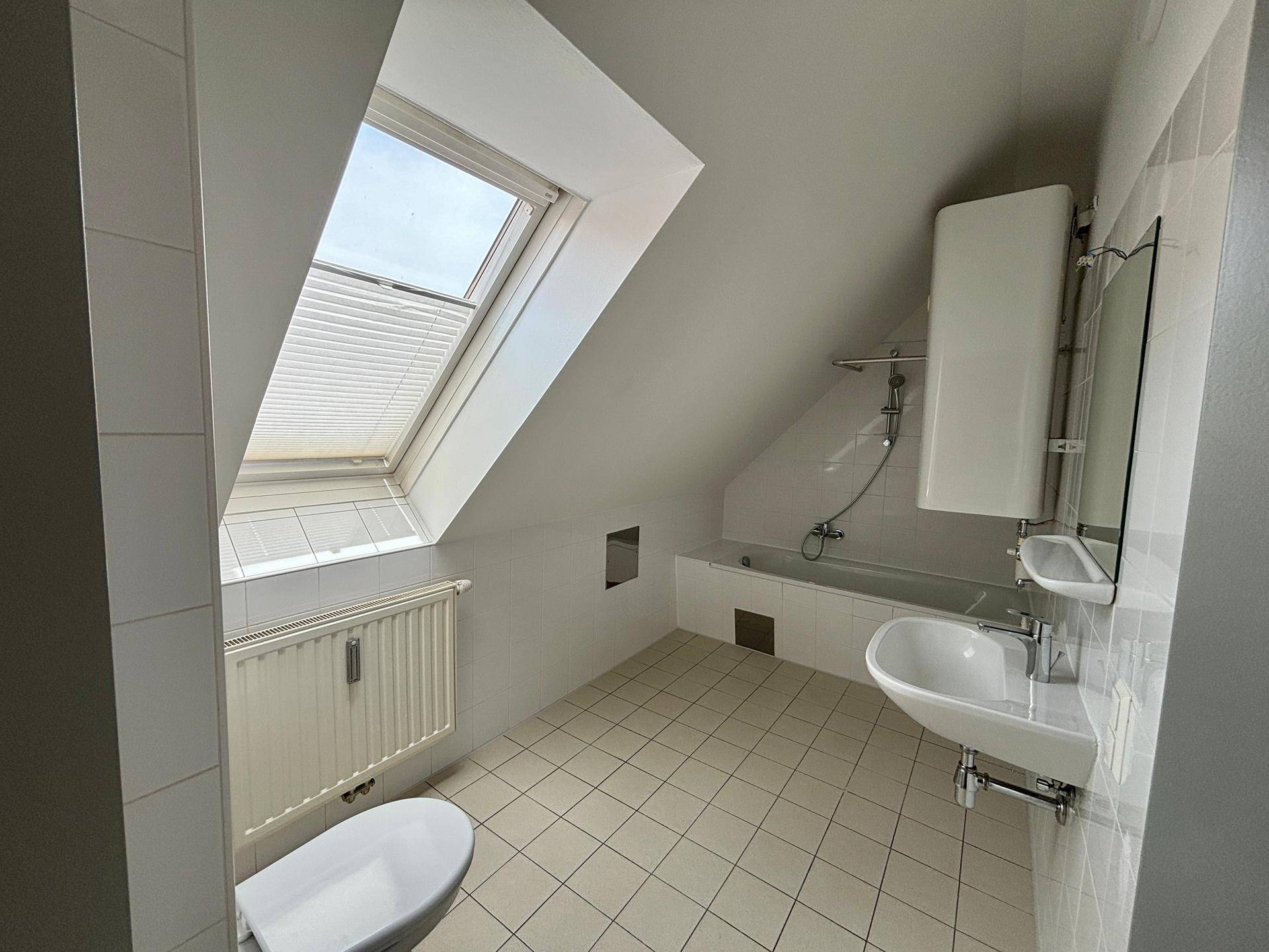 Badezimmer im Dachgeschoss mit Badewanne, WC, Waschbecken und Dachfenster für Tageslicht.