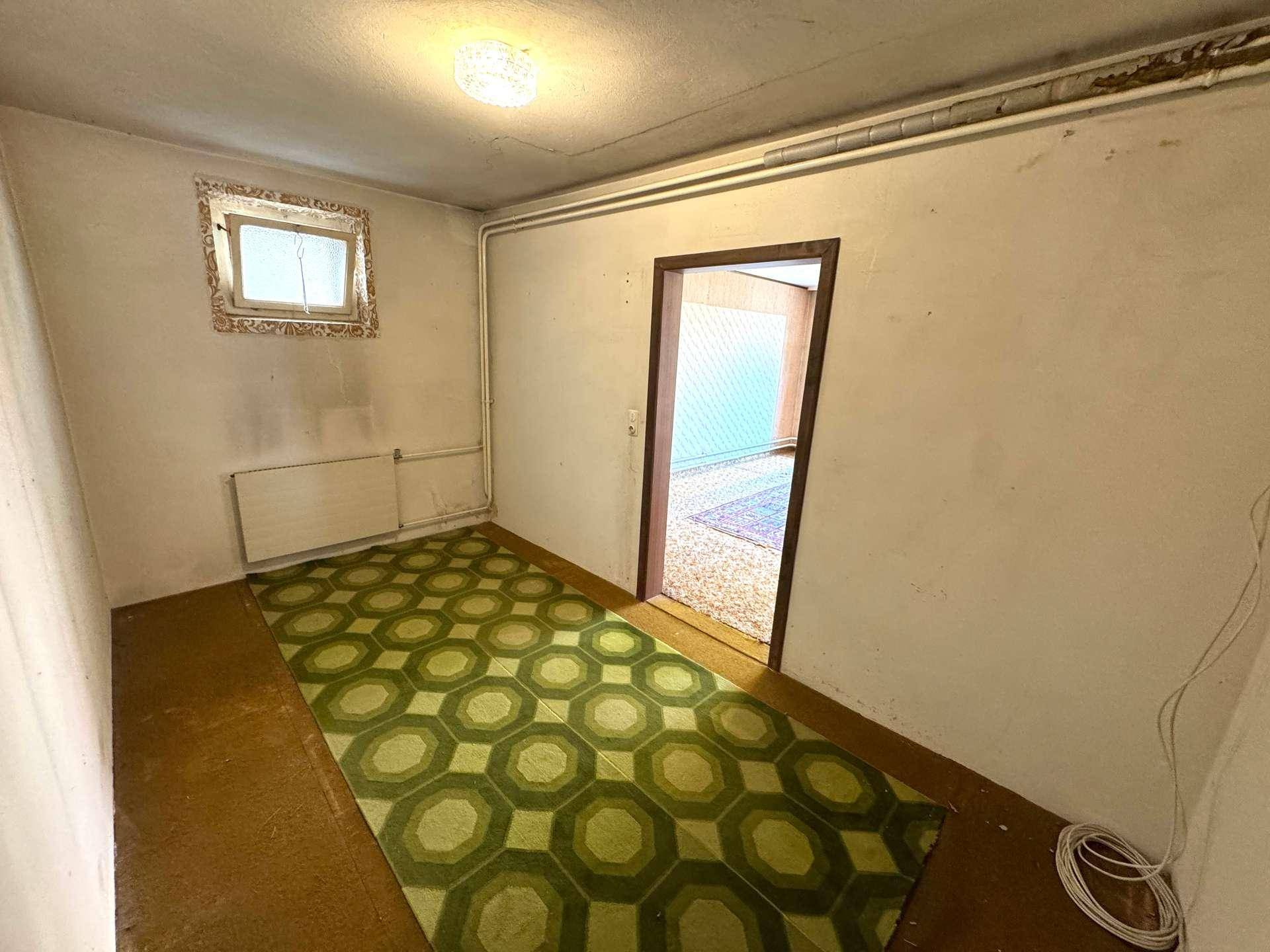 Kleiner Raum mit Fenster, Teppichboden und Heizkörper.