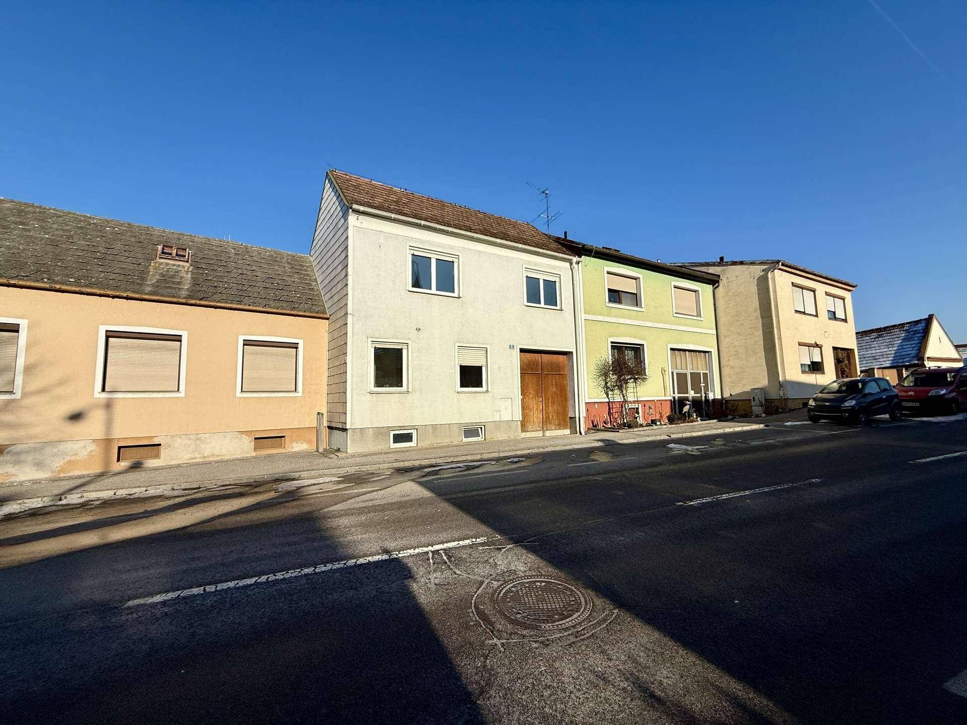 Reihenhausfassade an einer Straße unter klarem blauem Himmel.