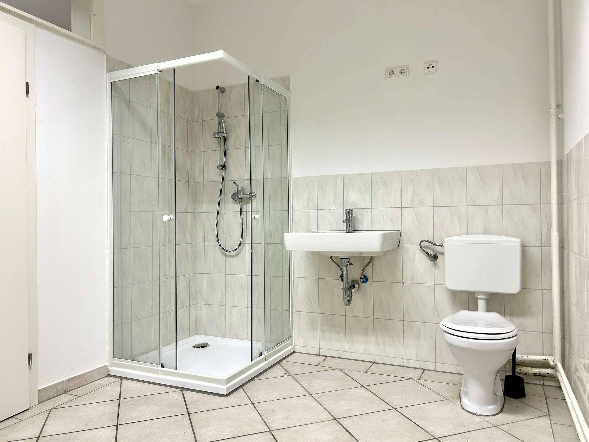 Helles Badezimmer mit Duschkabine, Waschbecken und WC, ausgestattet mit Fliesen.