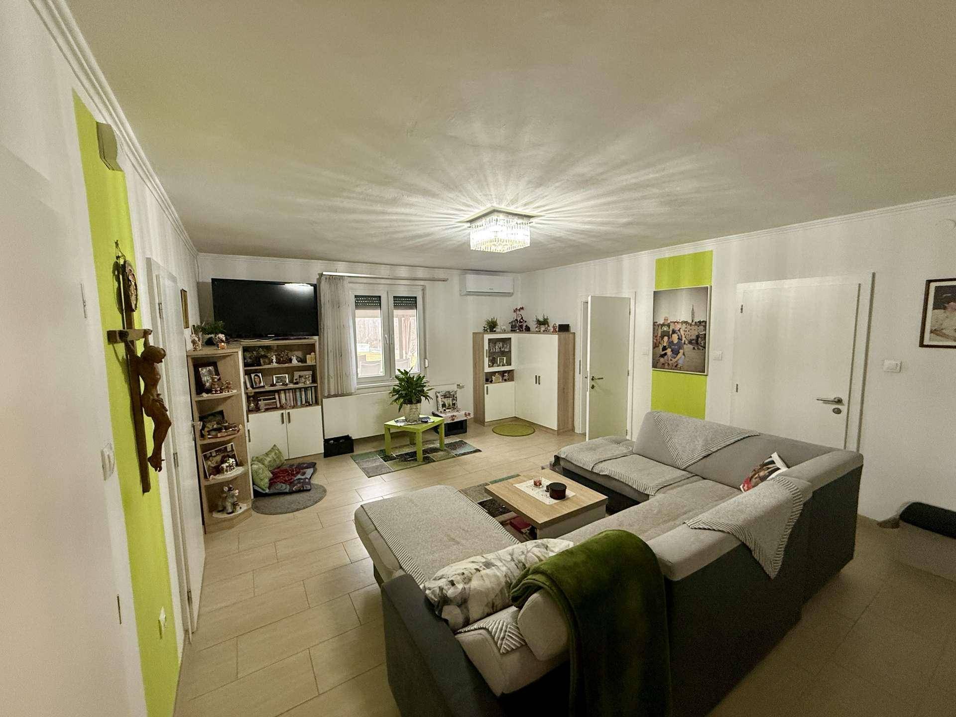 Gemütliches Wohnzimmer mit großem Ecksofa, Fliesenboden und farbigen Akzenten.