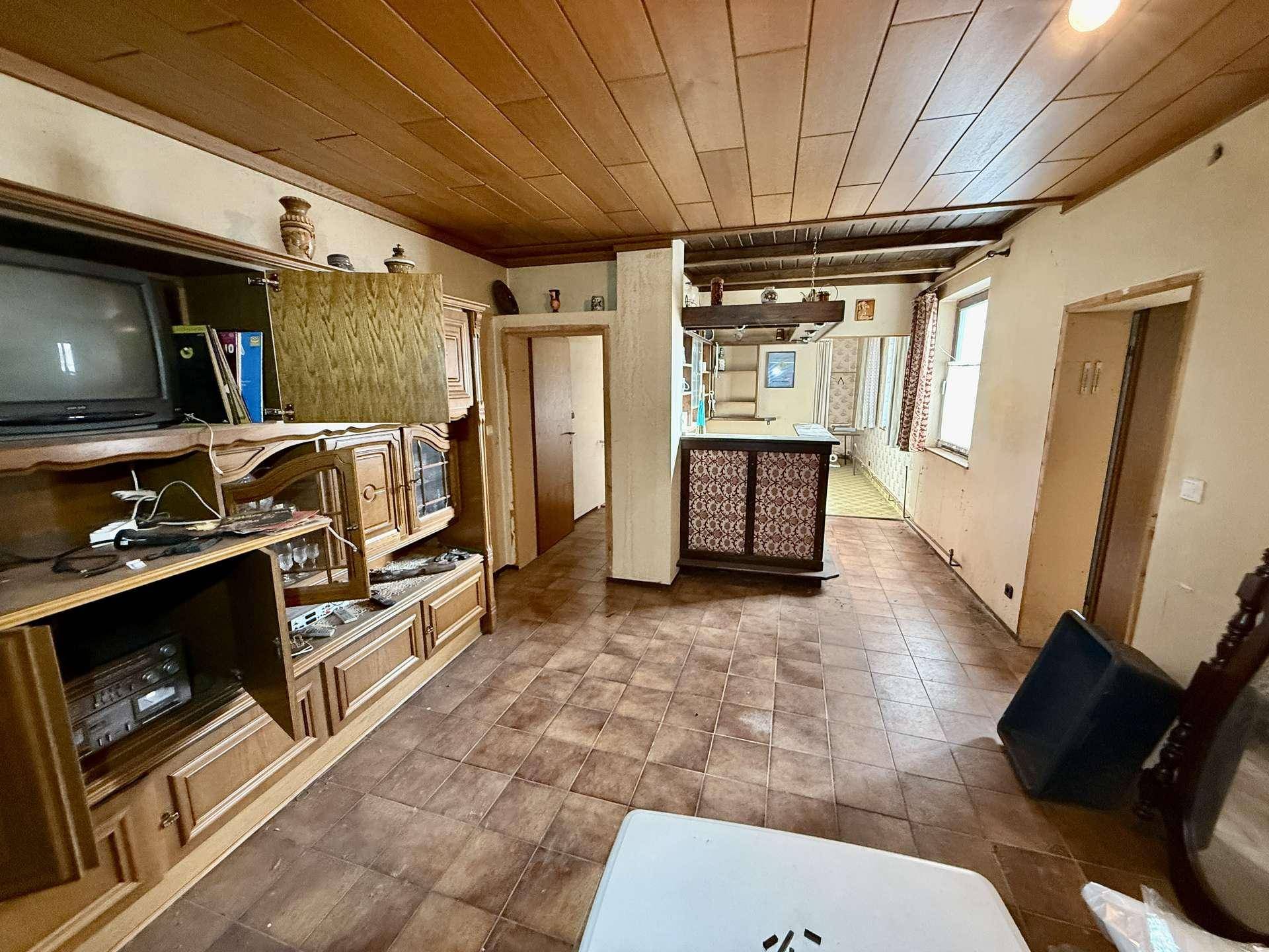 Geräumiges Wohnzimmer mit Holzdecke, Fliesenboden und einer integrierten Bar im traditionellen Stil.