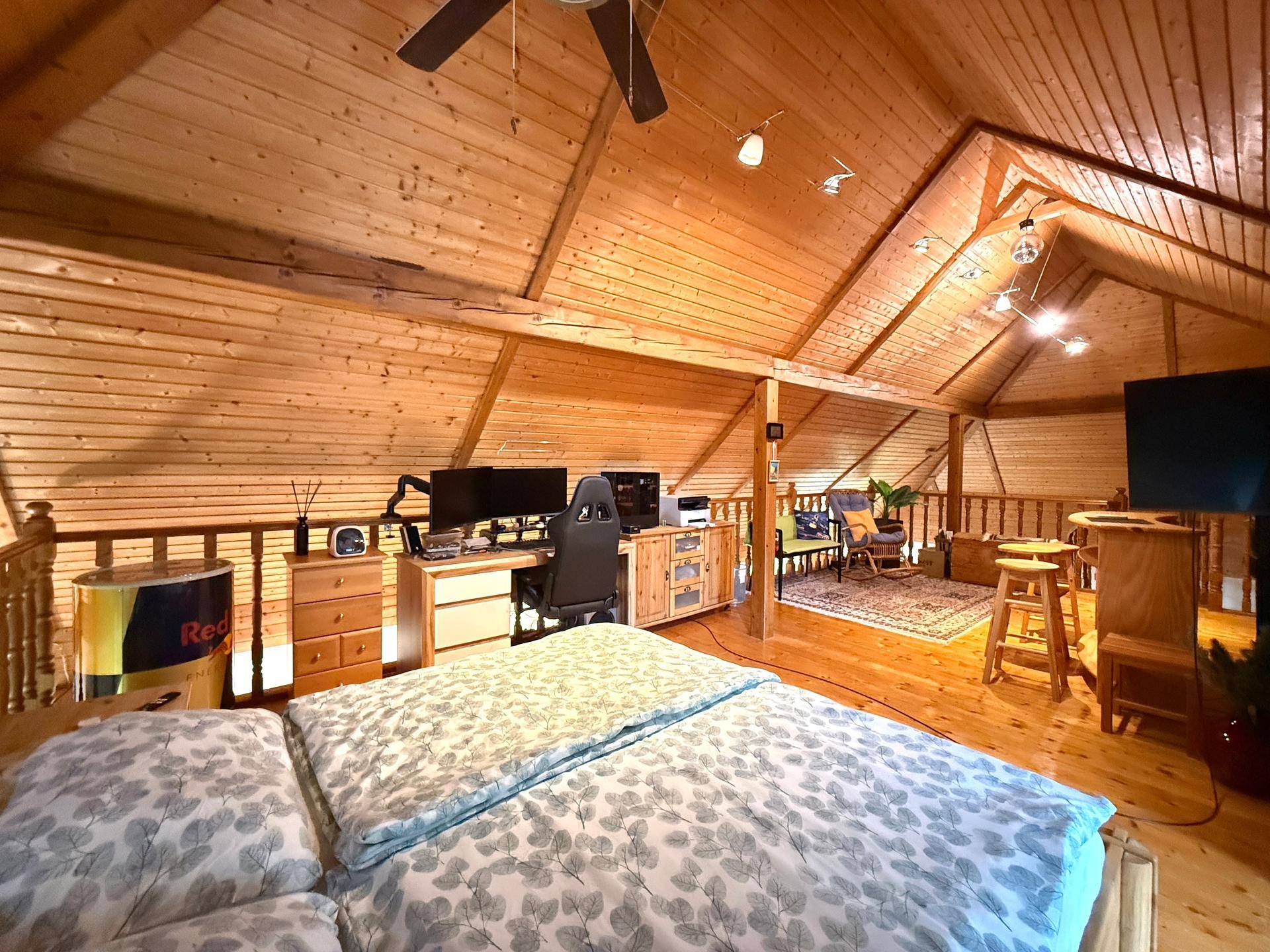 Helles Schlafzimmer im Dachgeschoss mit Holzverkleidung, Schreibtisch und Dachschräge.