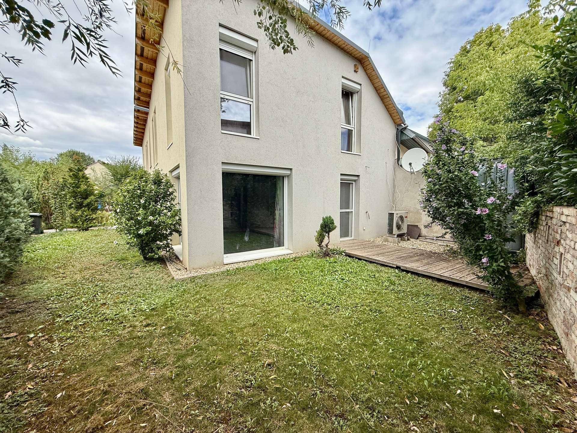 Rückansicht des Hauses vom Garten aus mit Rasenfläche und Holzterrasse.