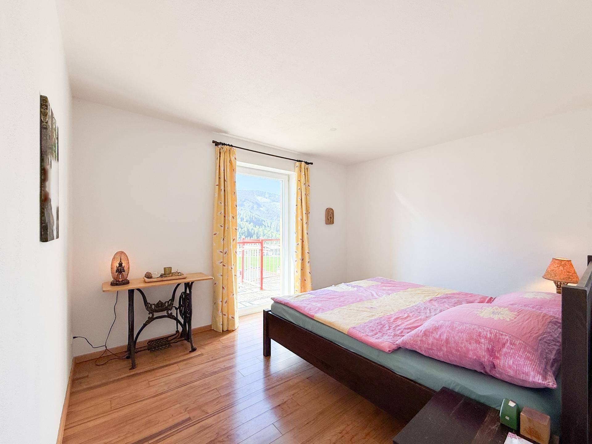 Gemütliches Schlafzimmer mit Holzboden und Zugang zu einem Balkon mit Bergblick.