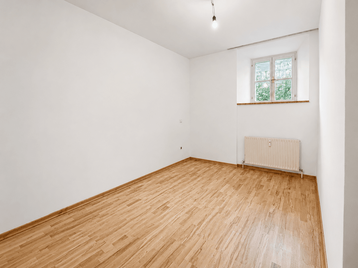 Geräumiges Zimmer mit Holzboden und Fenster, vielseitig nutzbar.