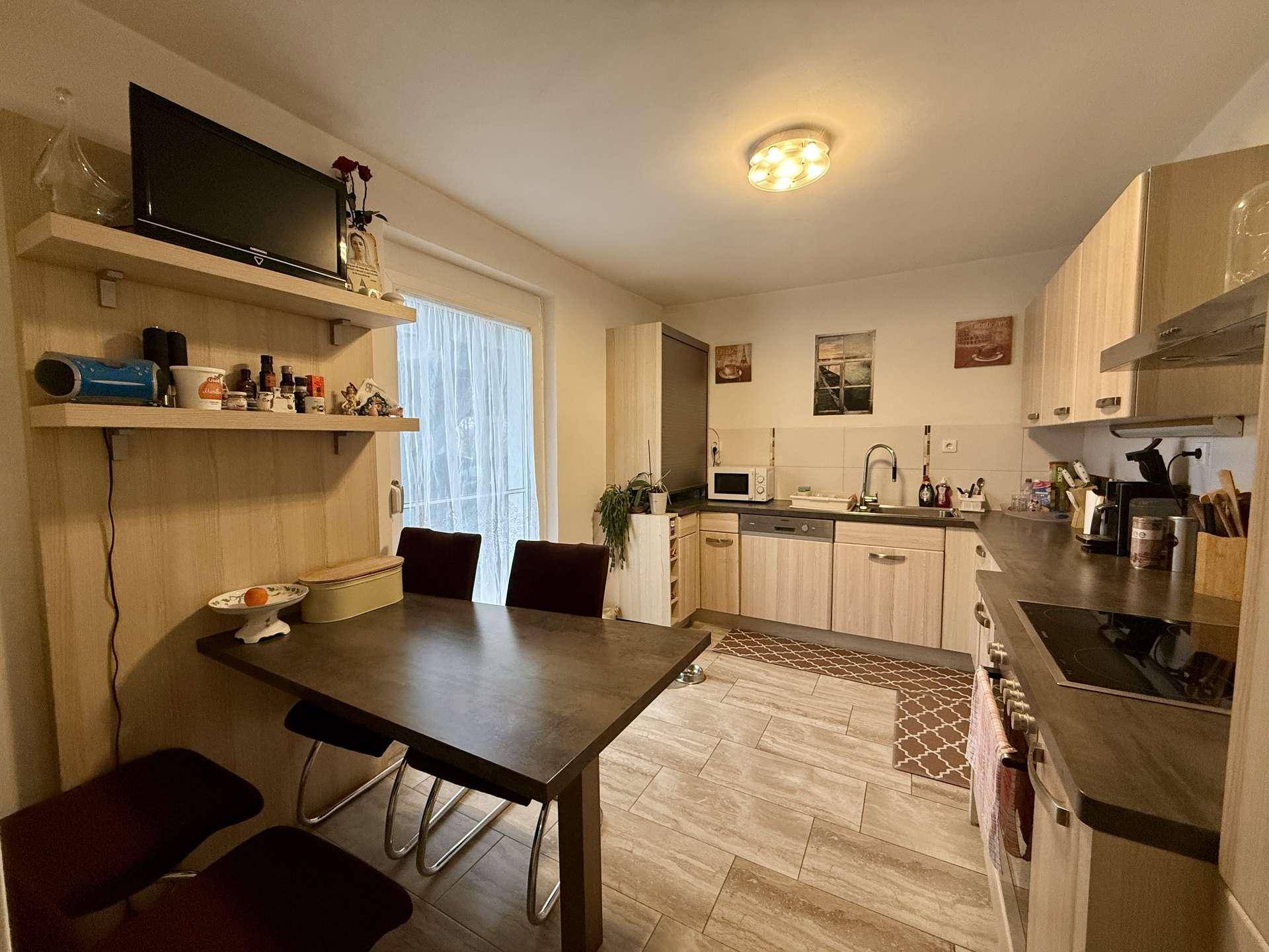 Funktionale Küche mit Essbereich, Einbaugeräten und Zugang zu einem Balkon oder Terrasse.