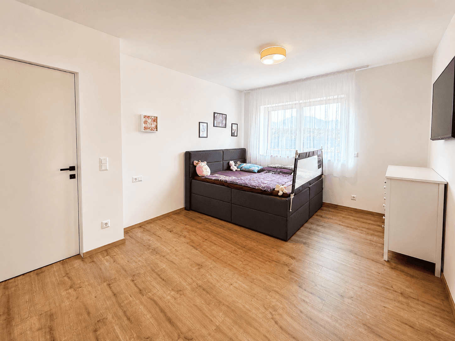 Gemütliches Schlafzimmer mit Holzboden, großem Fenster und Blick auf die umliegende Landschaft.