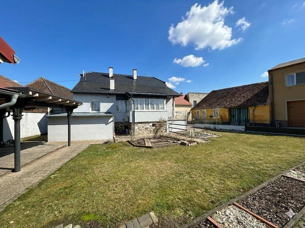 Hinteransicht des Hauses mit großem Garten, Rasenfläche und angrenzenden Gebäuden.