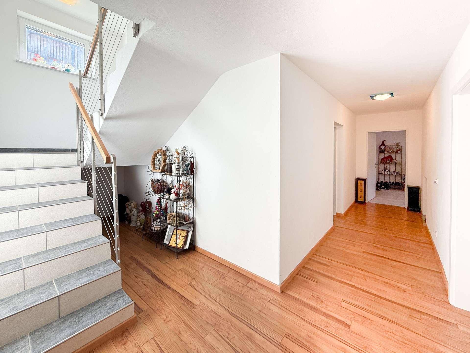 Heller Flur mit Holzboden und Treppe, die zu den oberen Etagen führt.