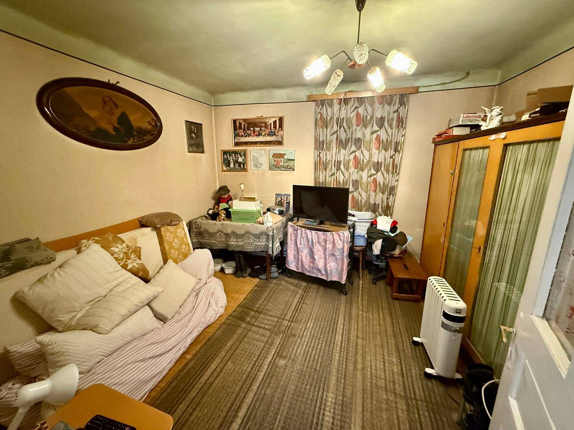 Wohnraum mit Sofa, Kleiderschrank, Fernseher und Heizkörper, in einem traditionellen Stil.