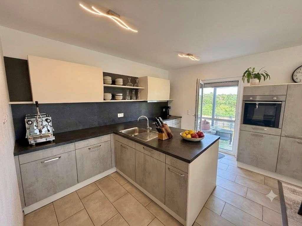 Moderne Küche mit Kücheninsel, integrierten Geräten und Zugang zur Terrasse mit Weitblick.