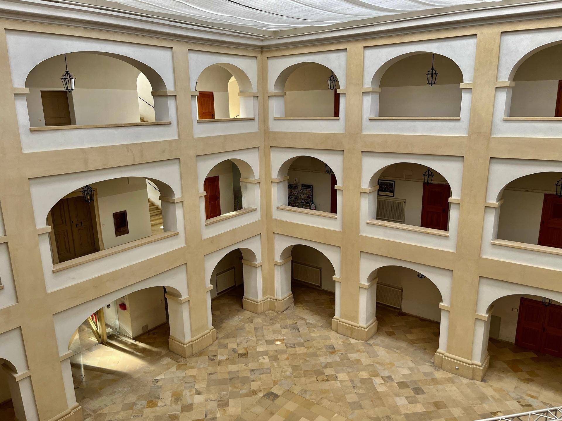 Innenhof eines historischen Gebäudes mit mehreren Etagen, Arkaden und Steinboden.