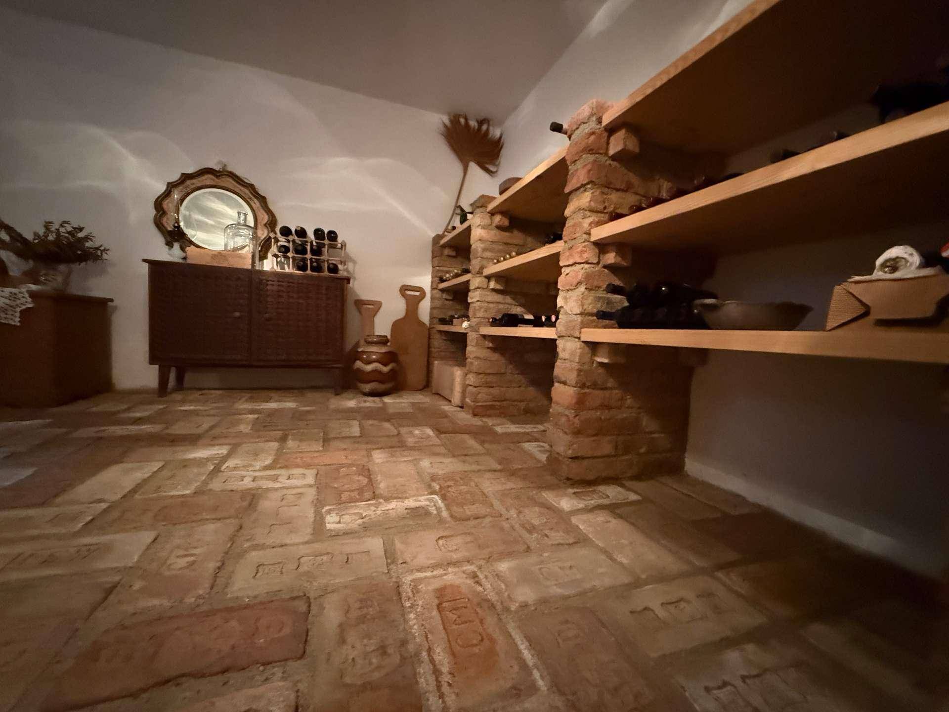 Rustikaler Weinkeller mit Ziegelboden und Holzregalen für Weinflaschen.