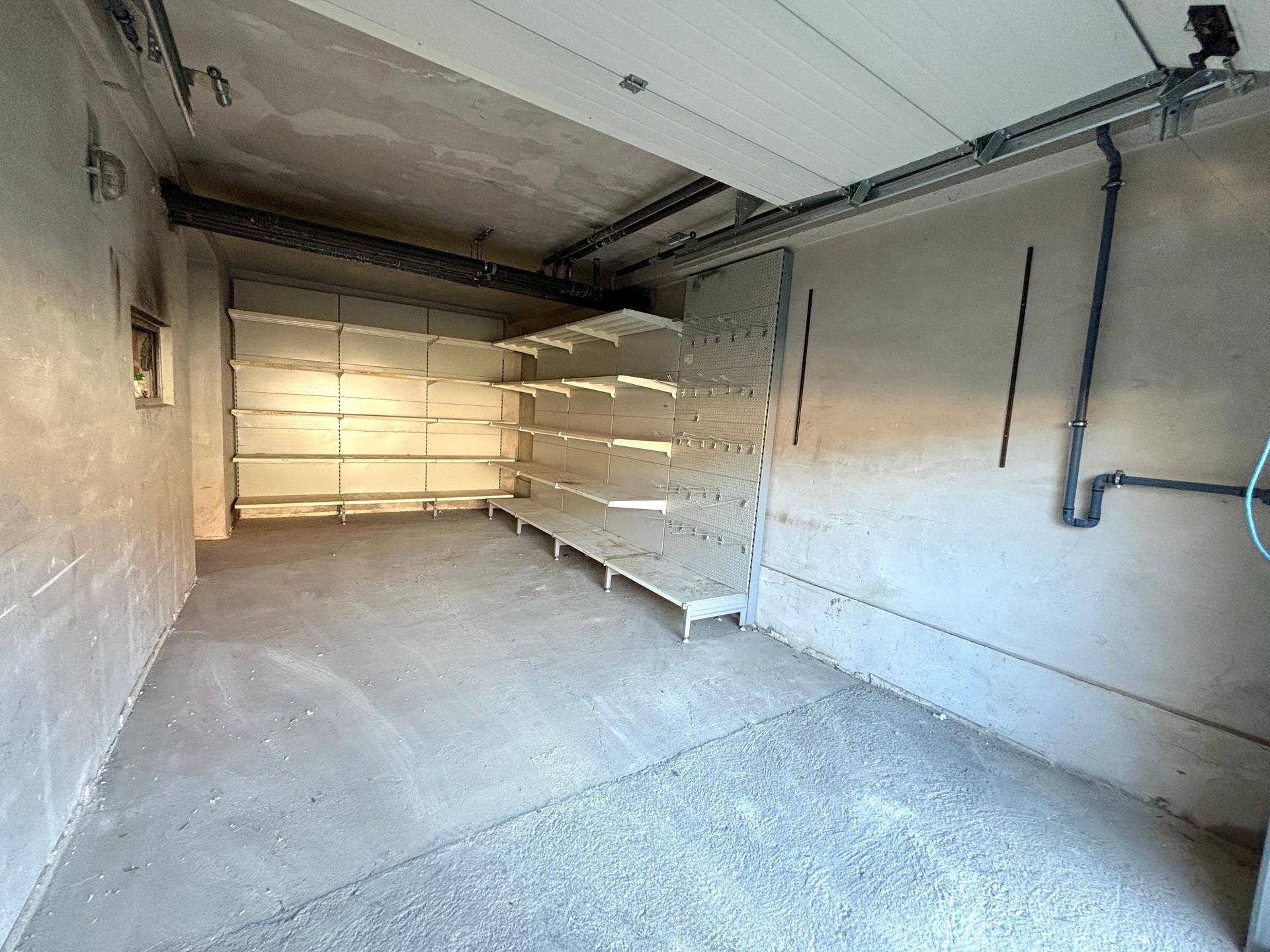 Innenansicht der Garage mit robustem Betonboden und umfangreichen Wandregalen zur Organisation.