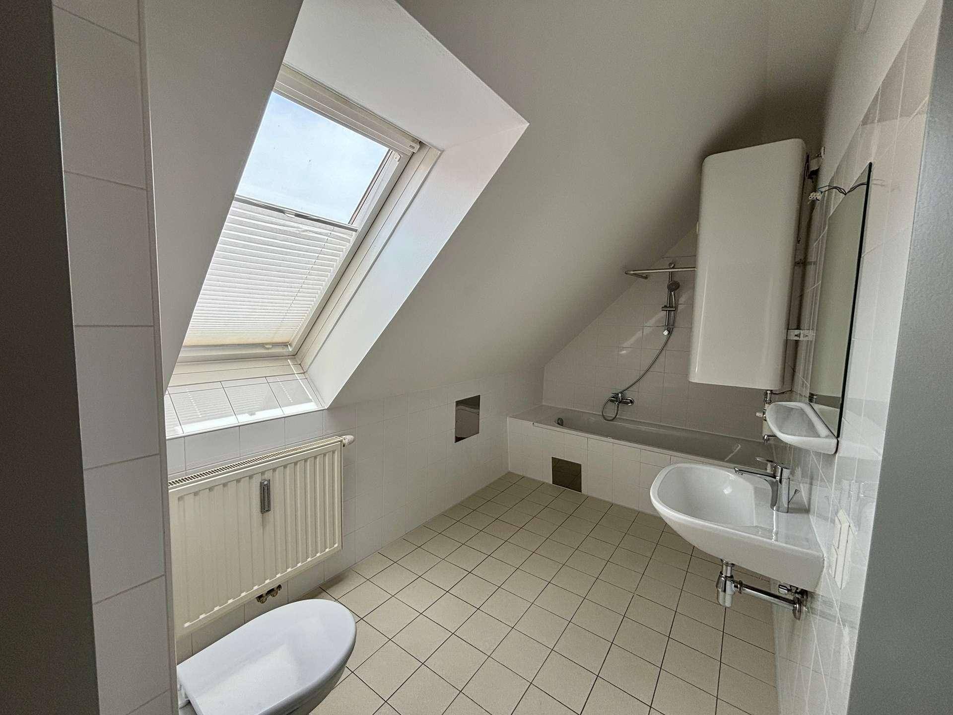 Badezimmer im Dachgeschoss mit Badewanne, Waschbecken, WC und Dachfenster für natürliches Licht.