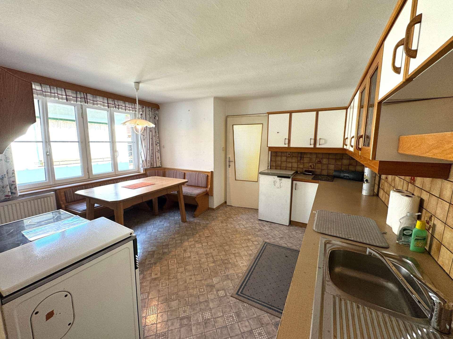 Traditionelle Wohnküche mit Einbauschränken, Essbereich und Fensterblick.