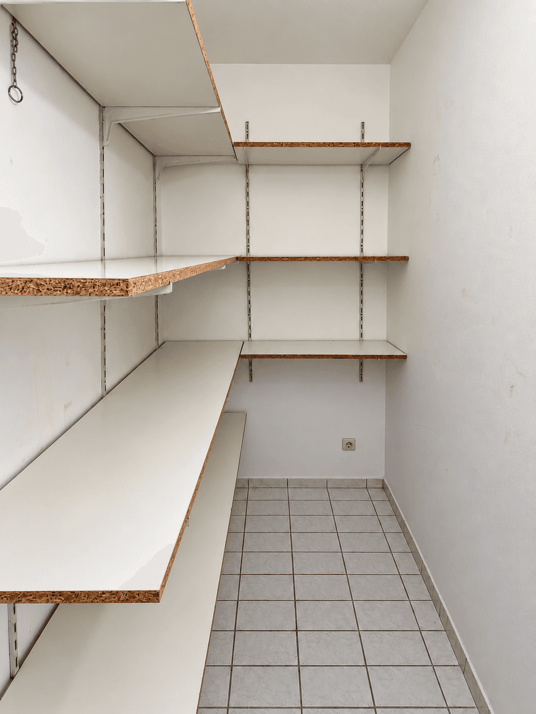 Praktischer Abstellraum mit Fliesenboden und stabilen Regalen für zusätzlichen Stauraum und Organisation.
