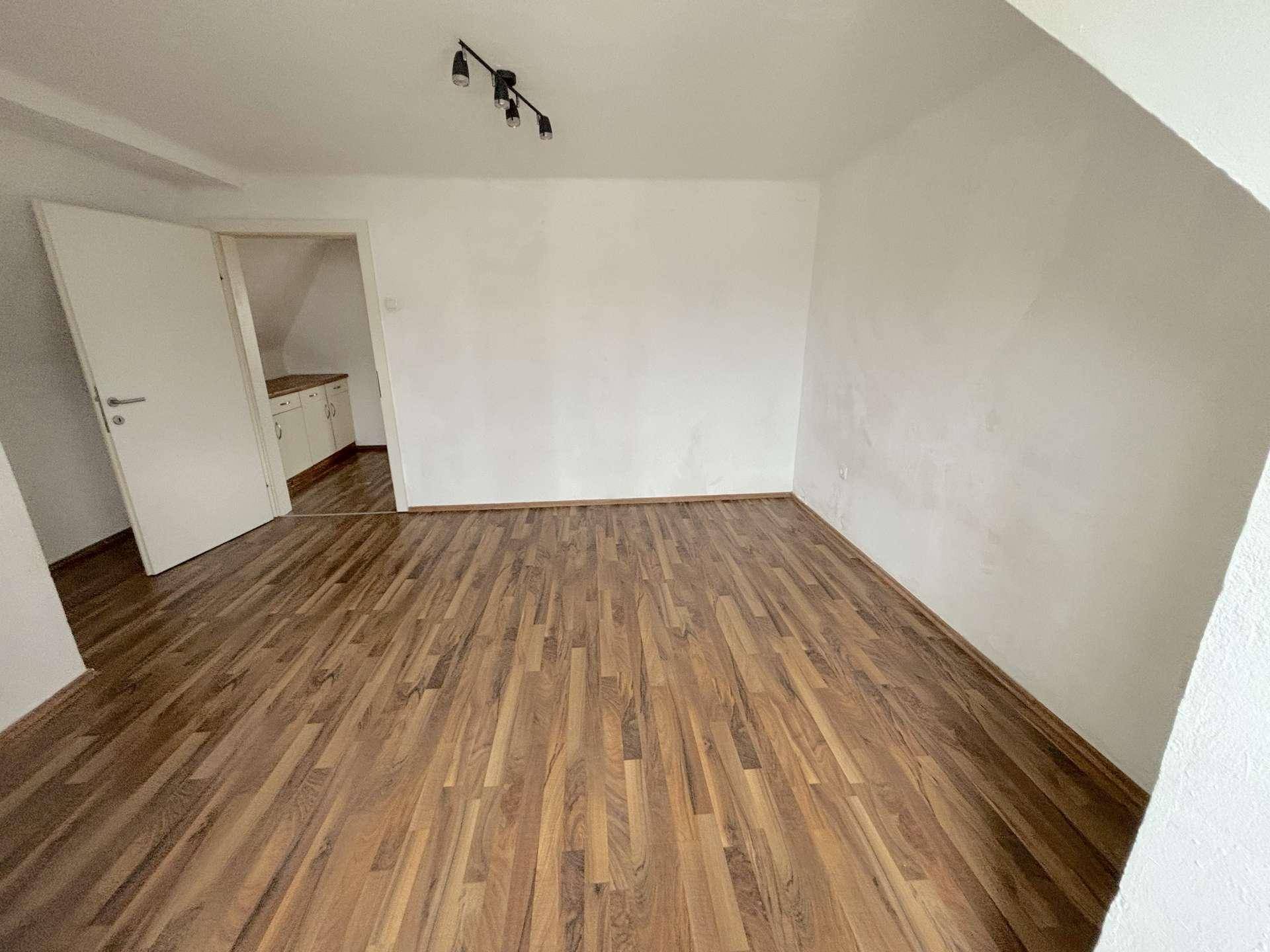 Helles Zimmer mit Laminatboden und Dachschräge, bietet vielseitige Nutzungsmöglichkeiten.