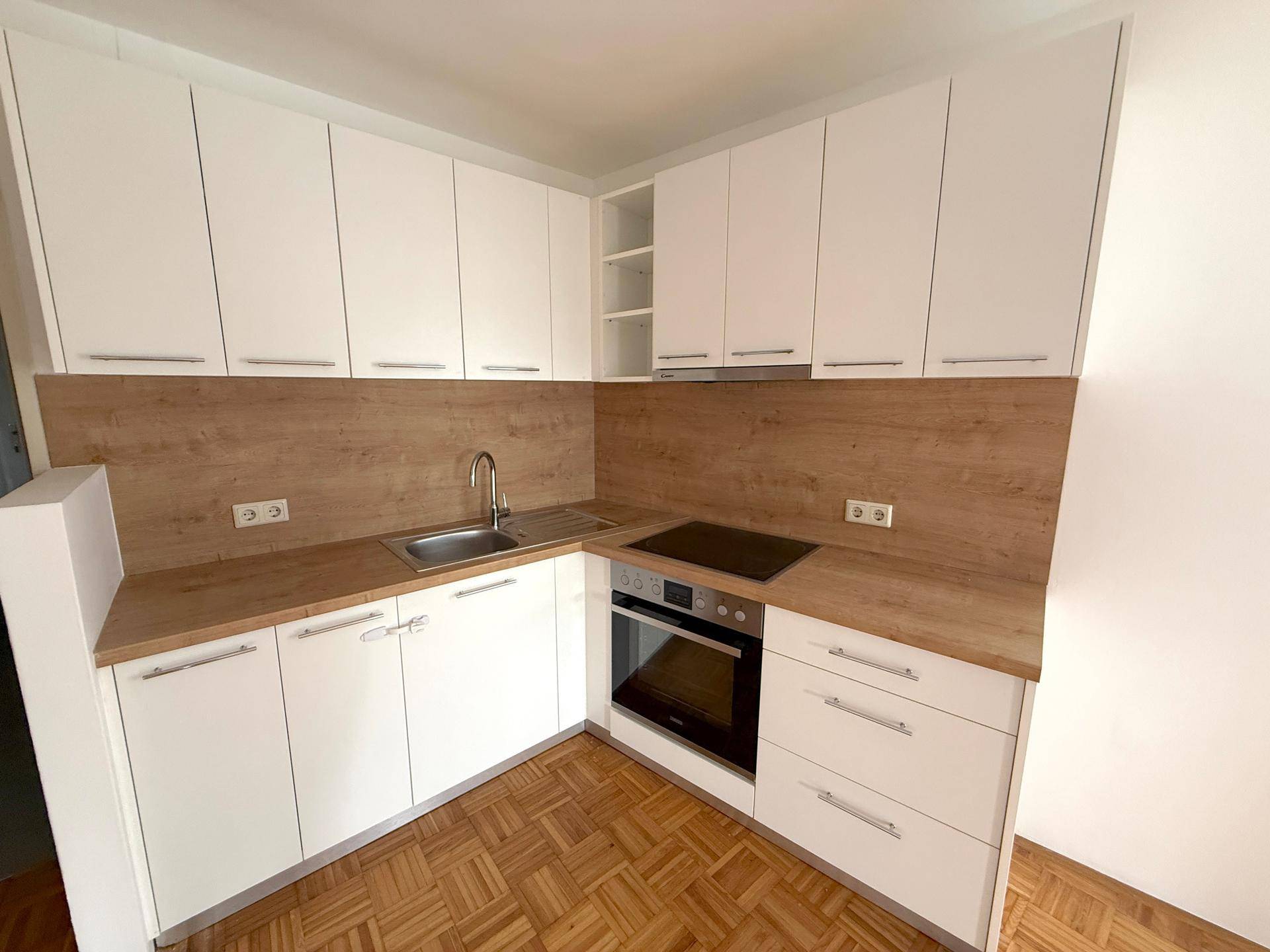 Moderne Einbauküche mit weißen Schränken, Holzarbeitsplatte und integrierten Geräten.