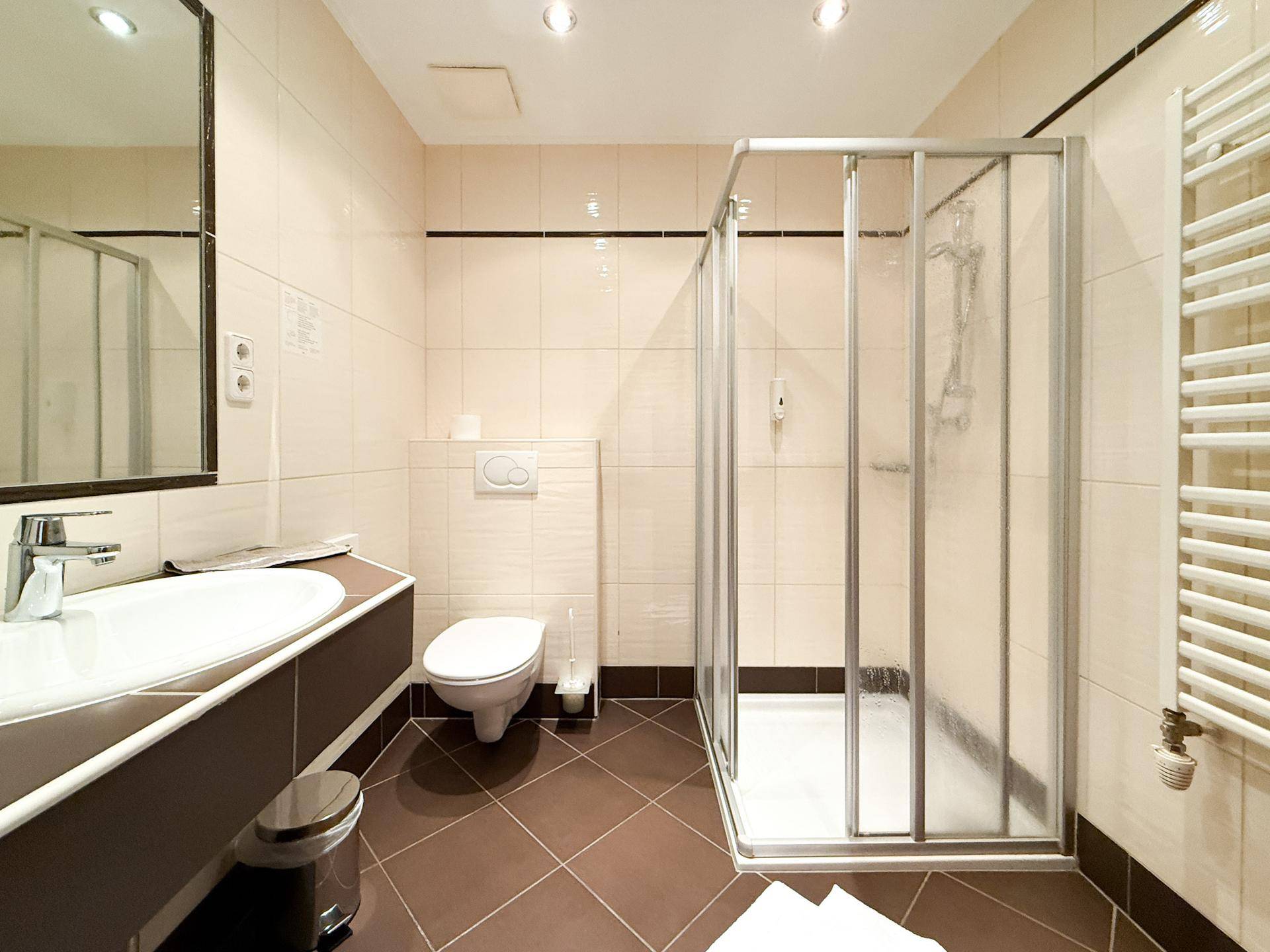 Modernes Badezimmer mit Duschkabine, Wand-WC und Handtuchheizkörper.