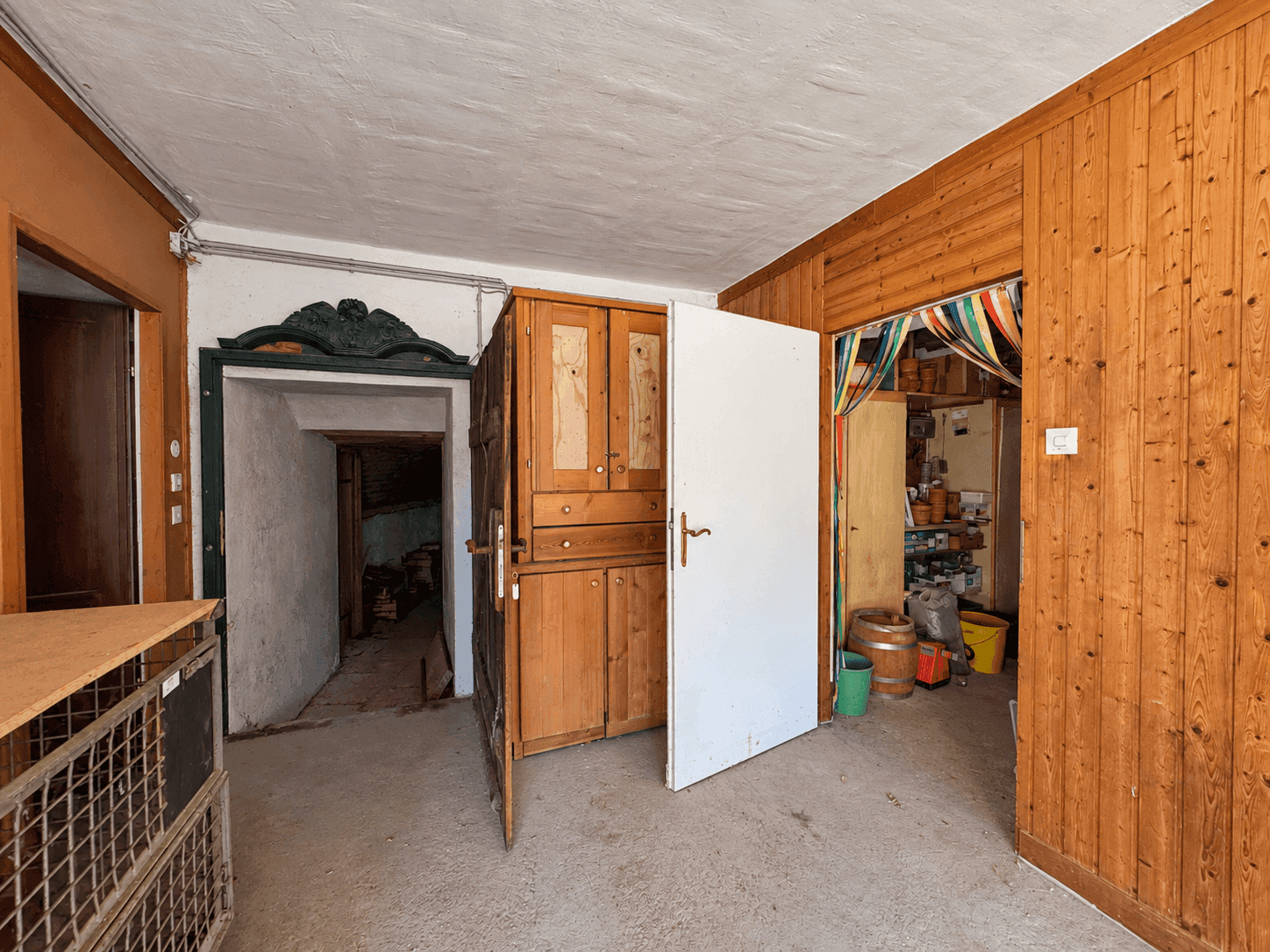 Eingangsbereich mit Holzvertäfelung, Schrank und Zugang zu weiteren Räumen.