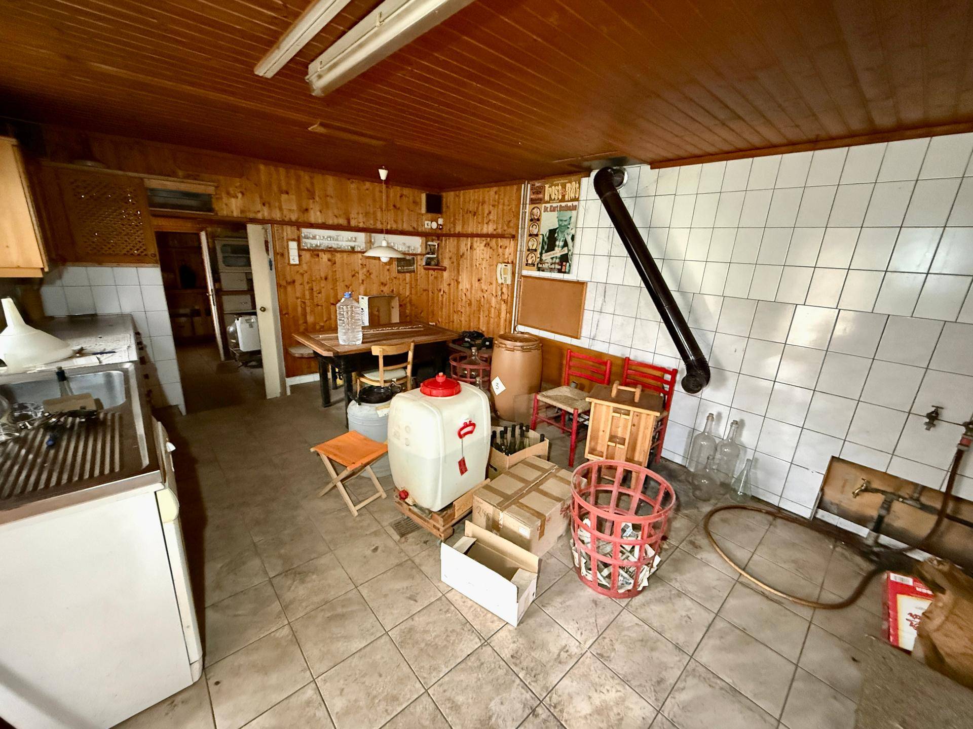 Rustikaler Wirtschaftsraum mit Fliesenboden, Holzvertäfelung und Arbeitsbereich.