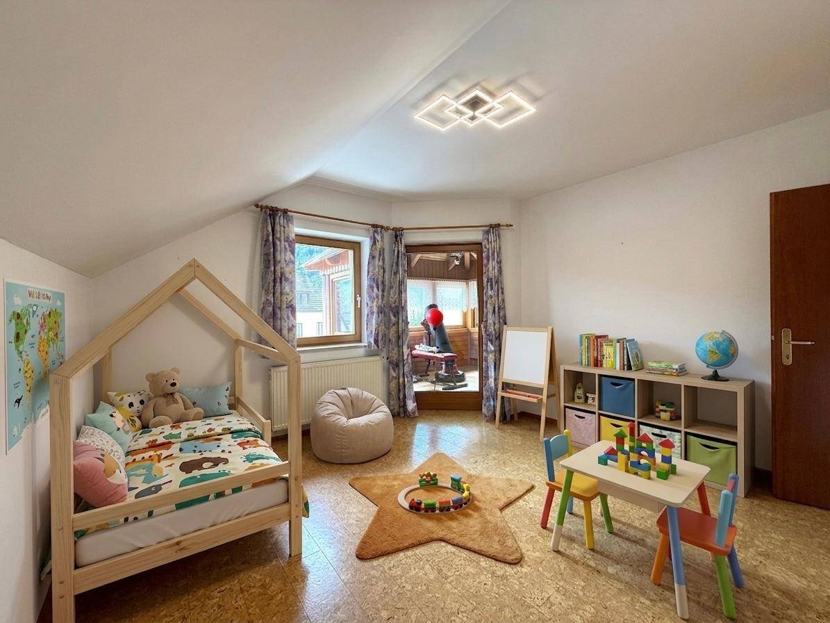 Helles Kinderzimmer im Dachgeschoss mit Spielbereich, Fenster und gemütlichem Holzbett.