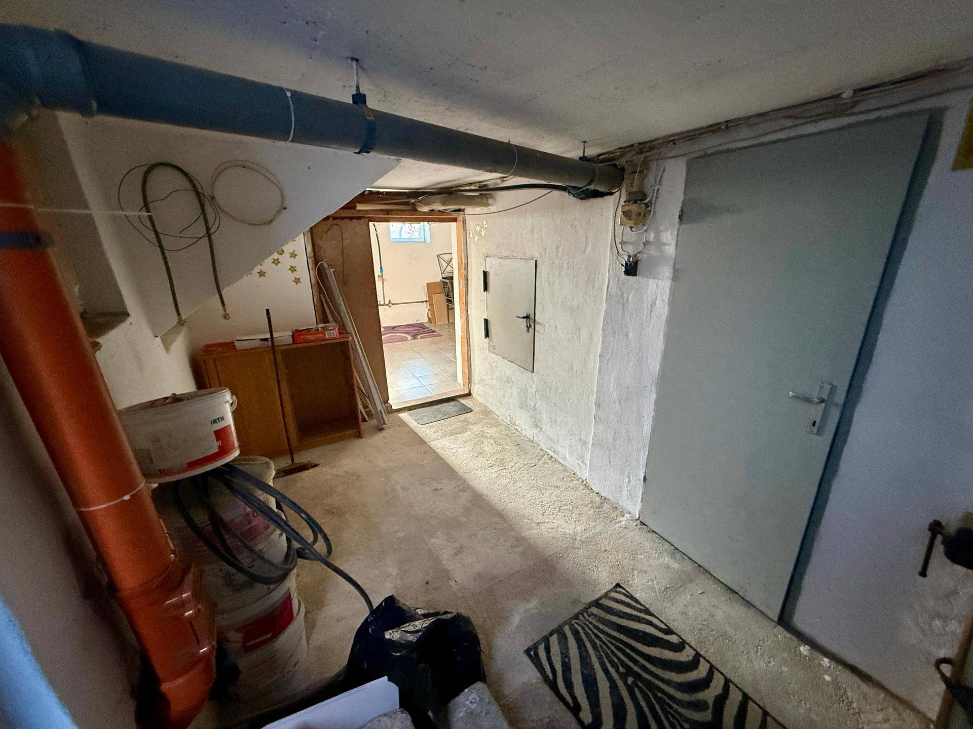 Unfertiger Kellerraum mit sichtbaren Rohren und Betonboden, bietet Stauraum.