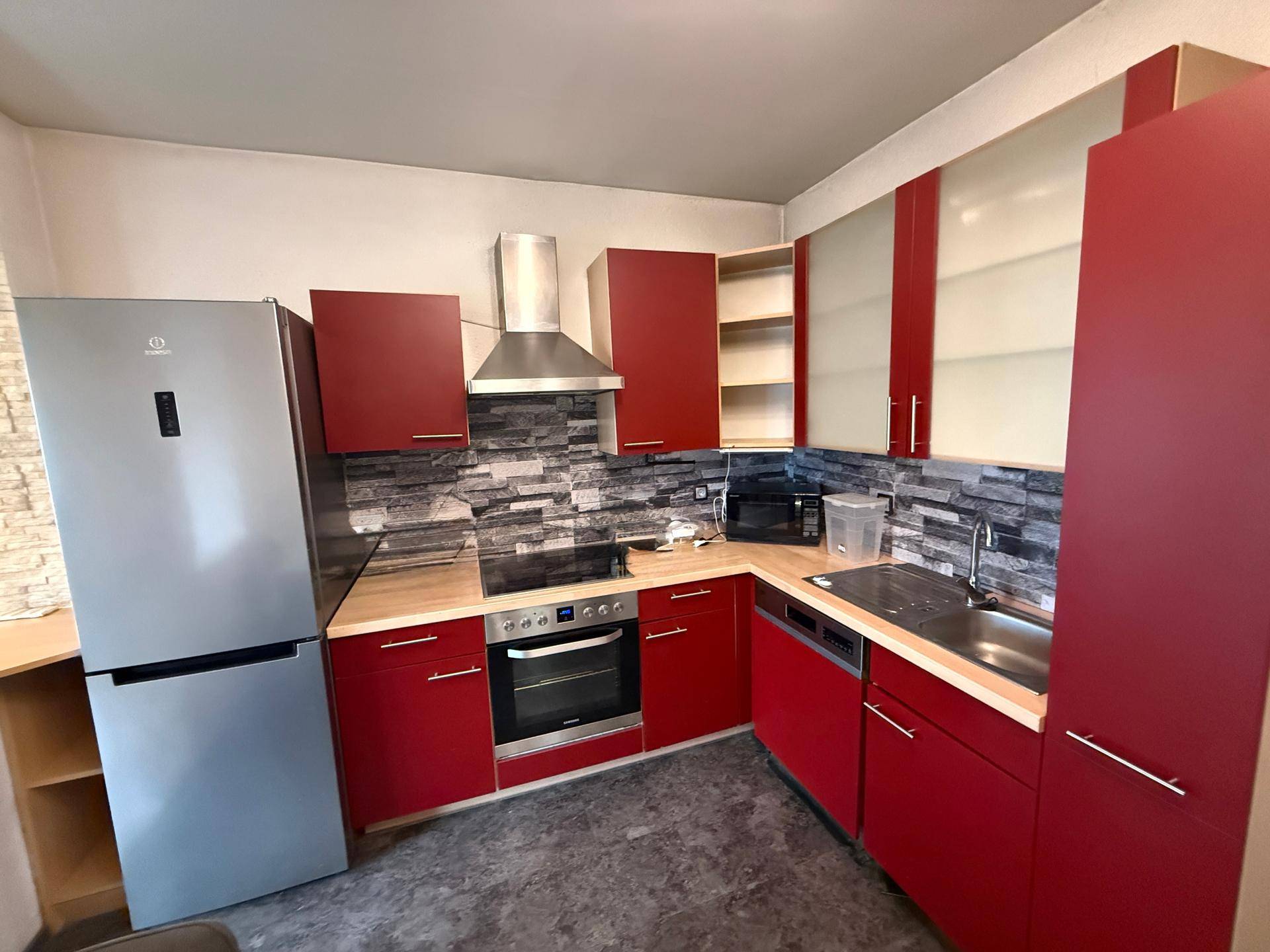 Detailansicht der roten Einbauküche mit Holz-Arbeitsplatte, Induktionskochfeld und Spülmaschine.