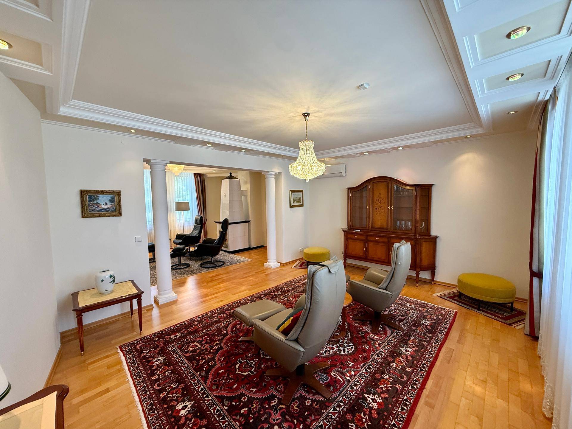 Elegantes Wohnzimmer mit Parkettboden, Stuckdecken und klassischer Einrichtung.